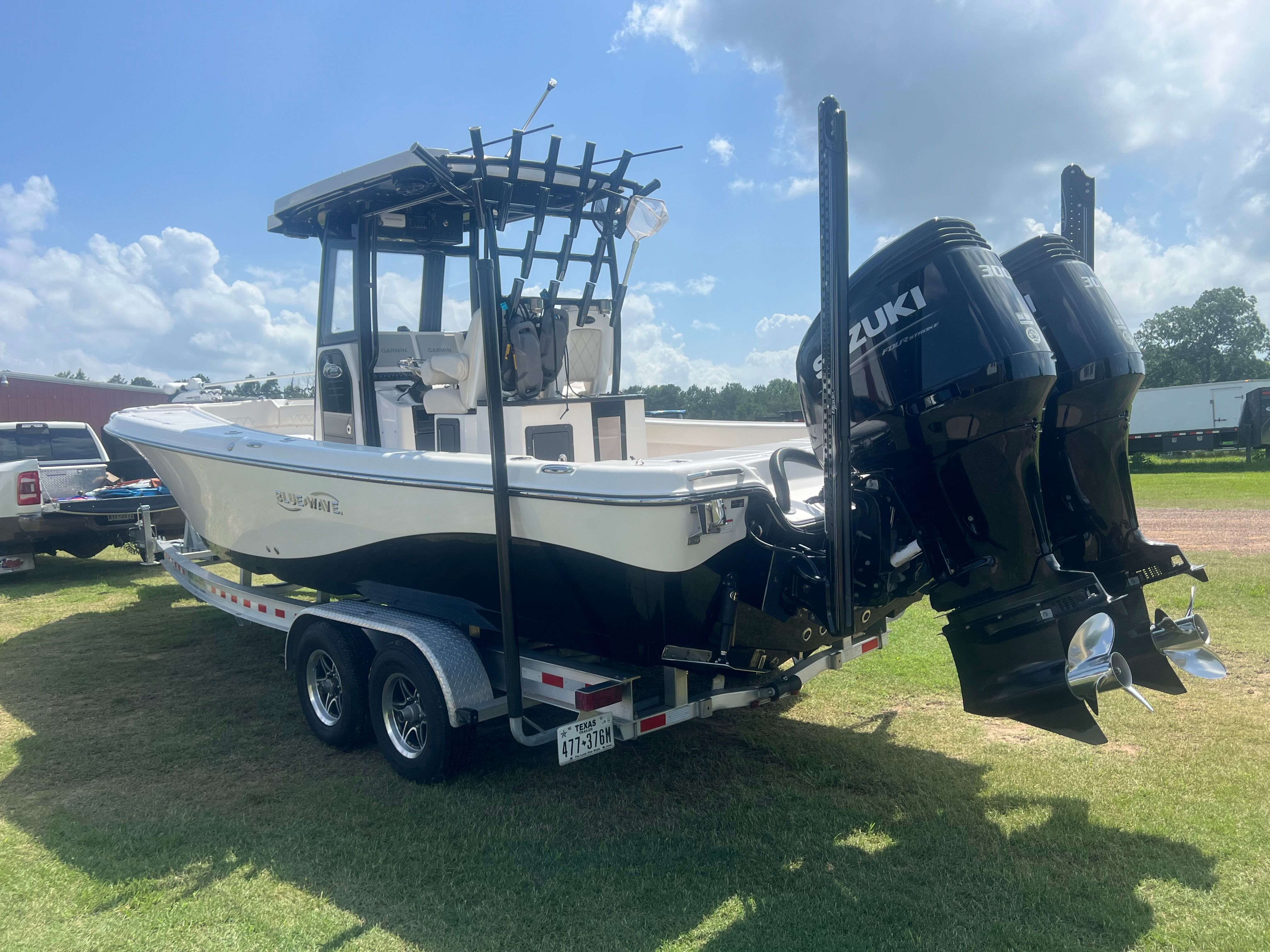 A 2023 Blue Wave 2800 Makaira boat on a trailer with dual Suzuki outboard engines.