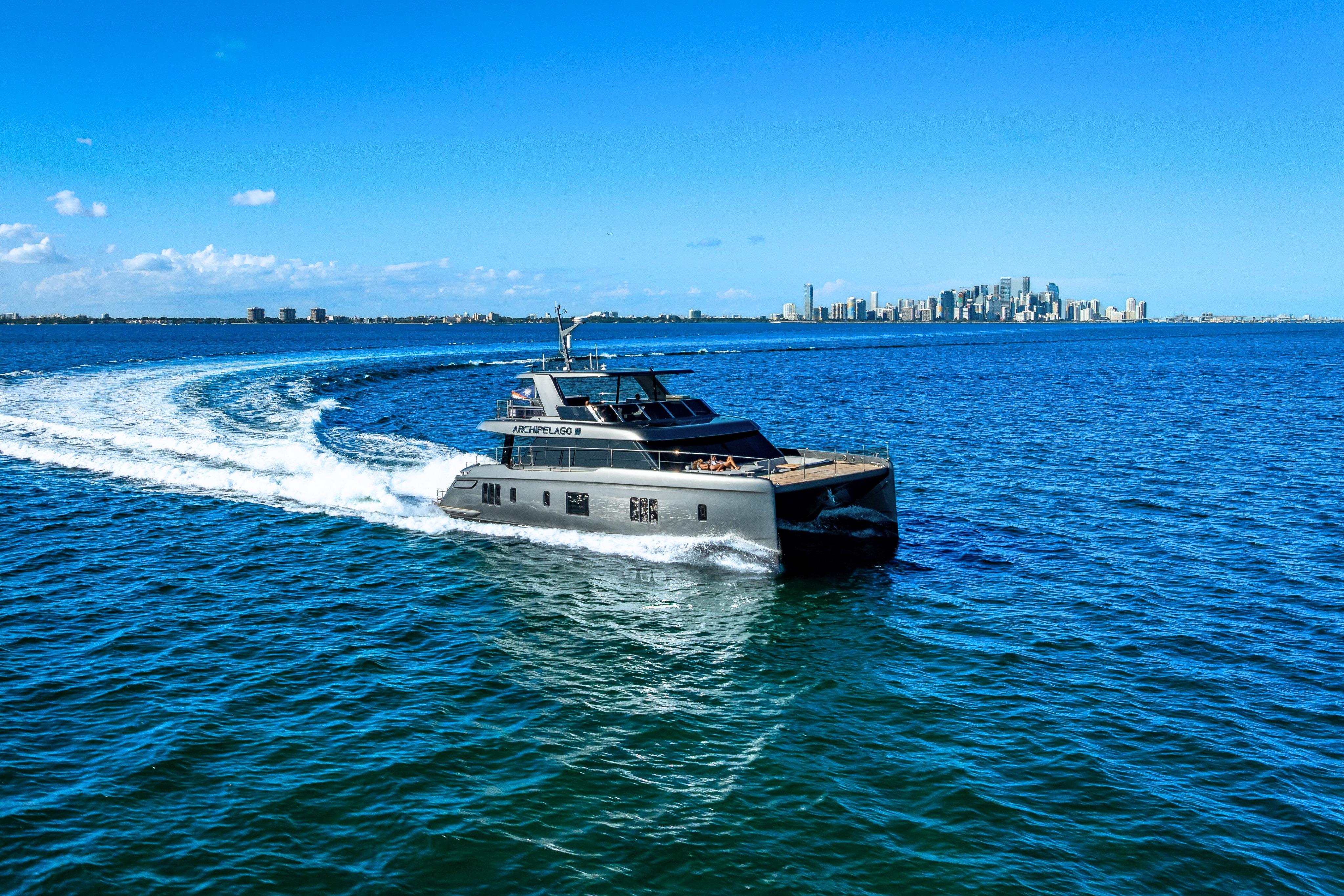 2026 Sunreef 60 Power yacht cruising on blue ocean with city skyline in background.