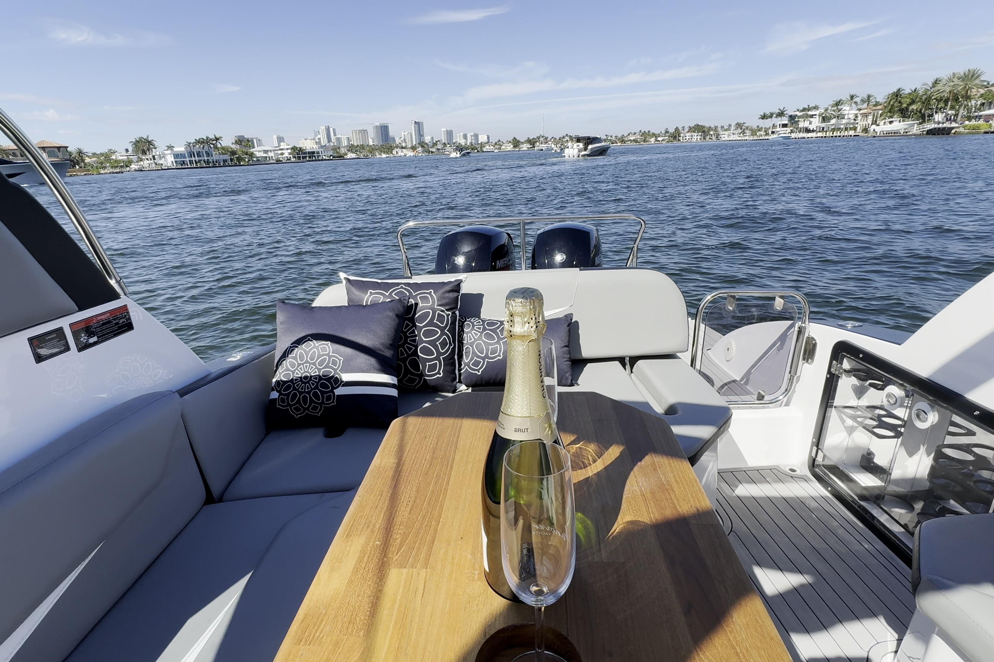 Luxurious Hanover 305 yacht interior with champagne, cushions, and scenic waterfront view, 2027 model.