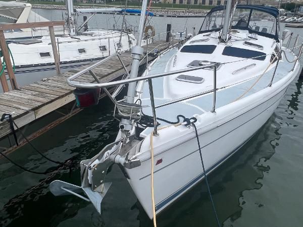 A white sailboat docked at a pier. It has a clean deck and is well-maintained.