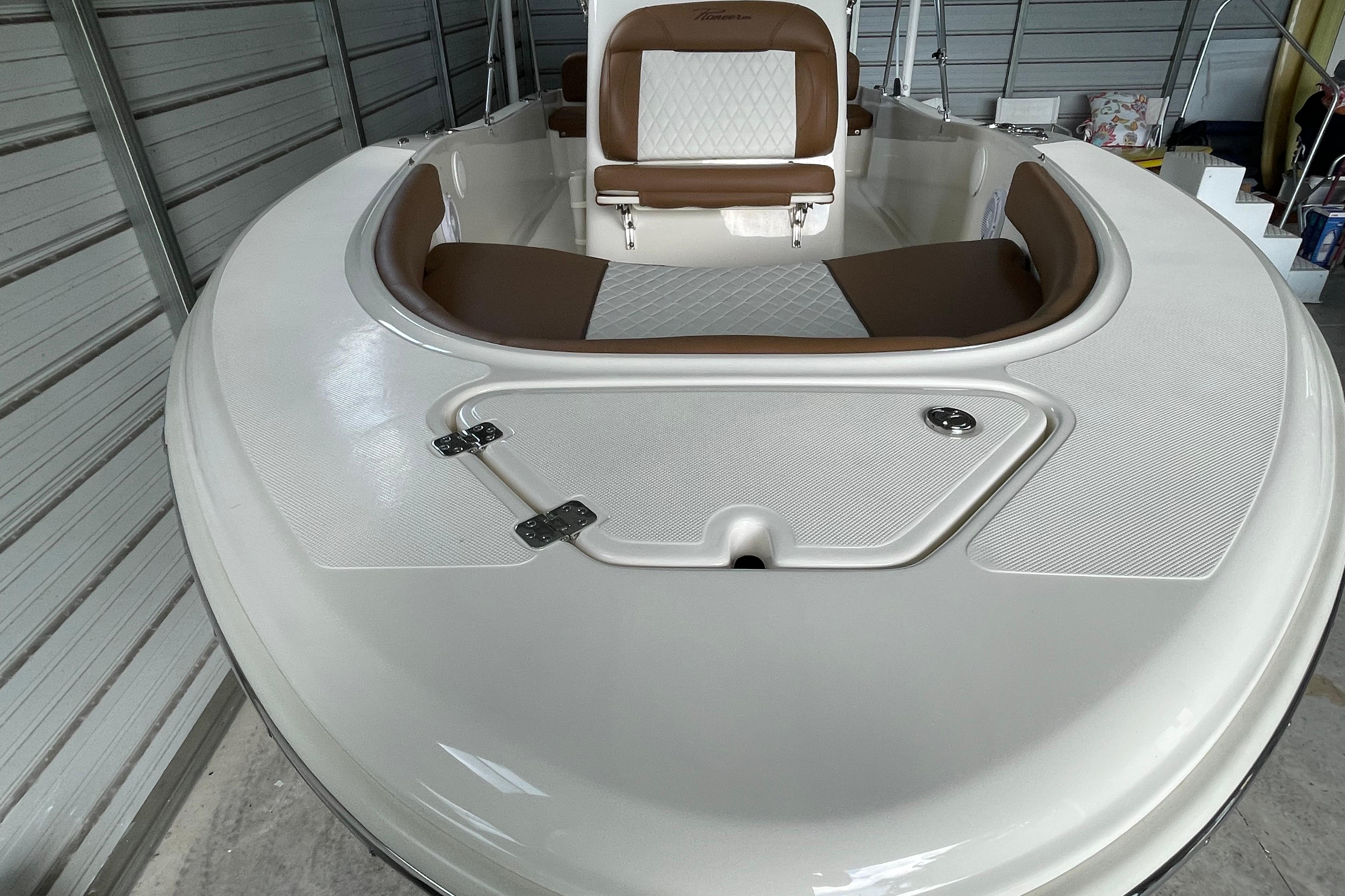 2024 Pioneer 180 Islander boat interior with white and brown seating in a garage.