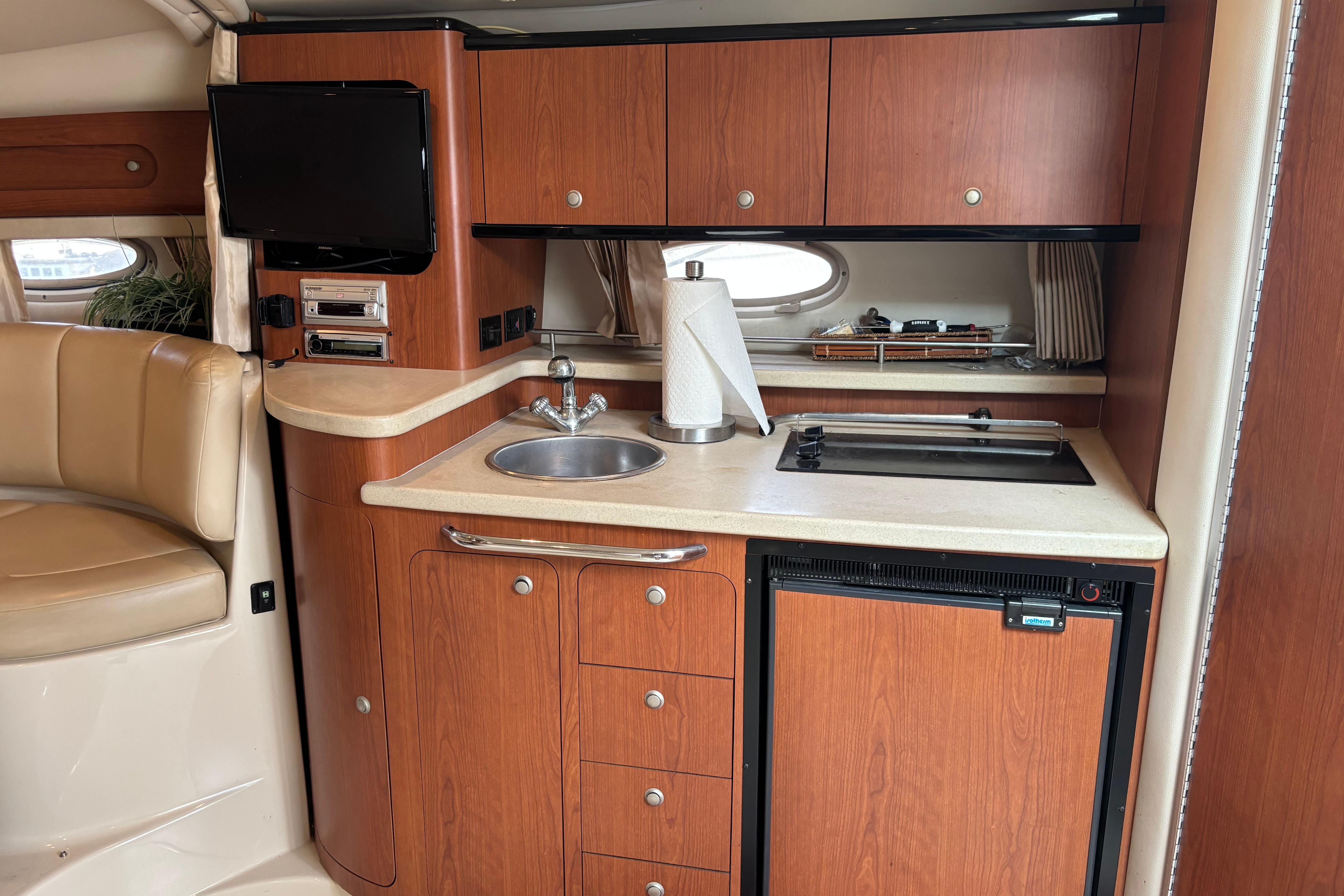 2004 Chaparral Signature 330 yacht interior with kitchenette, featuring wood cabinets and modern appliances.