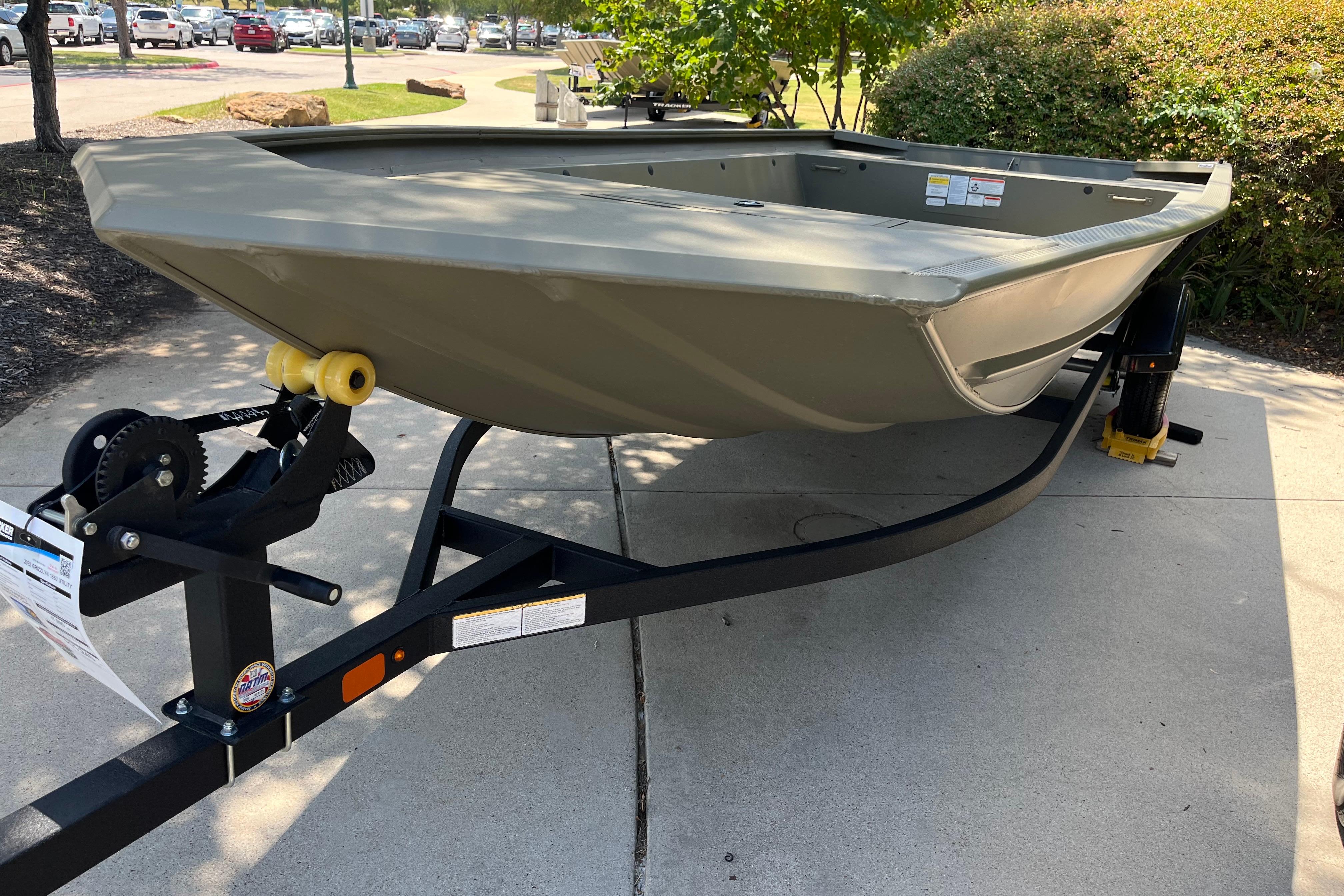 2025 Tracker GRIZZLY 1860 Utility boat on trailer, parked outdoors.