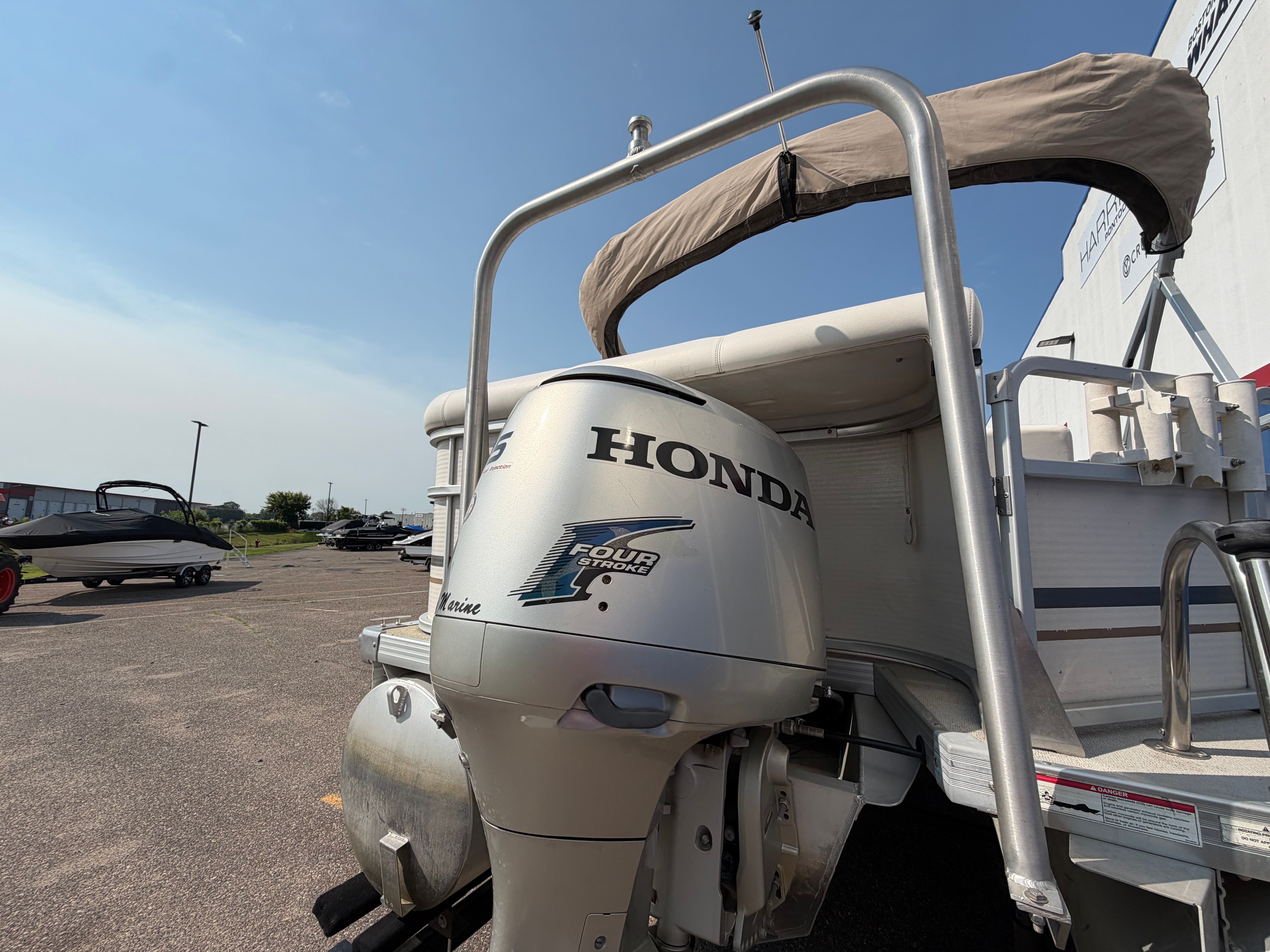 Rear view of a Premier 225 Sunsation pontoon boat with a Honda outboard motor.