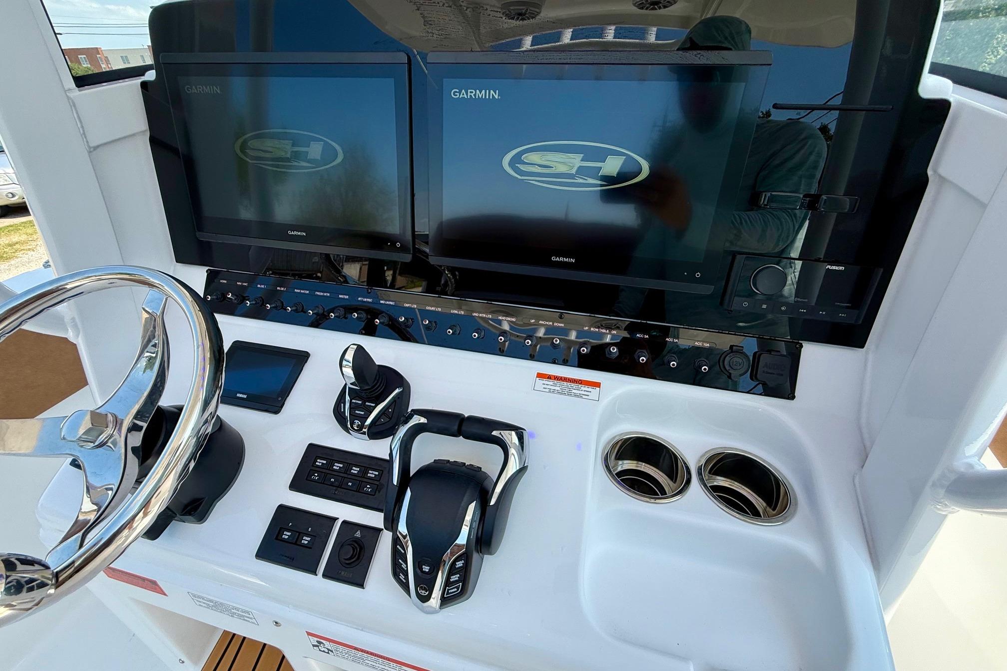 Control panel of 2026 Sea Hunt Ultra 305 SE with dual Garmin displays and steering wheel.