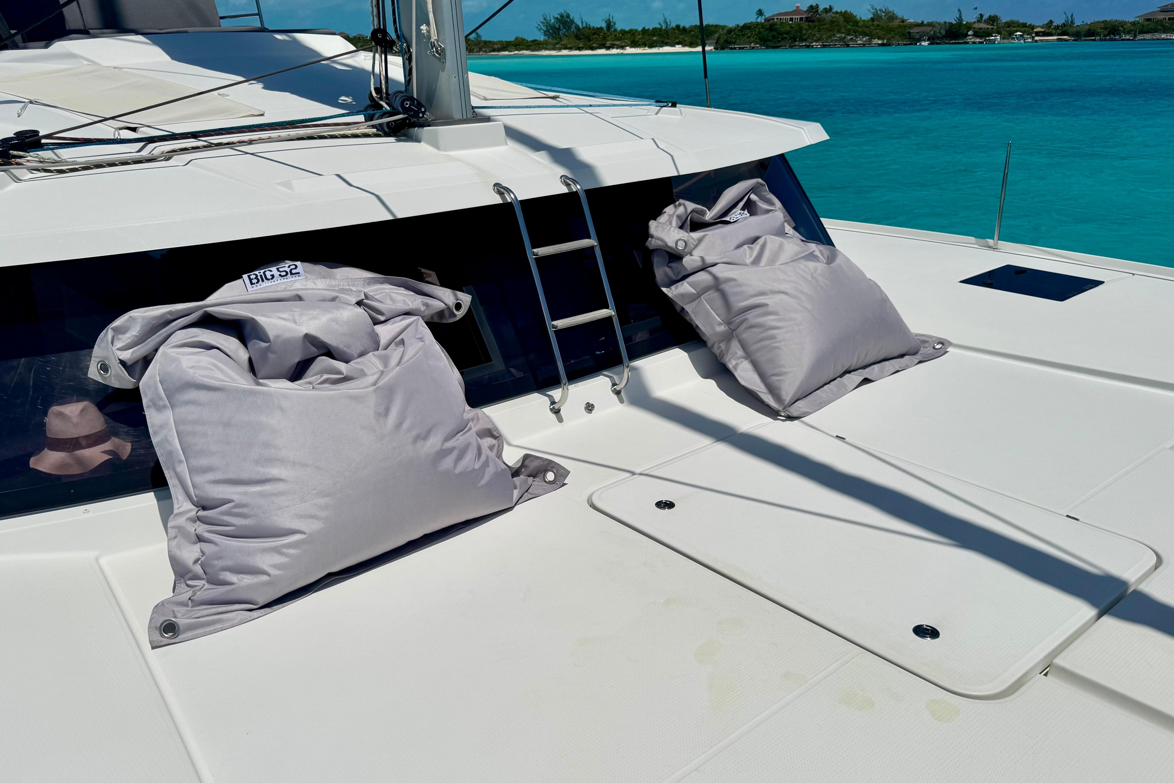 2020 Fountaine Pajot Saona 47 catamaran deck with cushions, turquoise water backdrop.