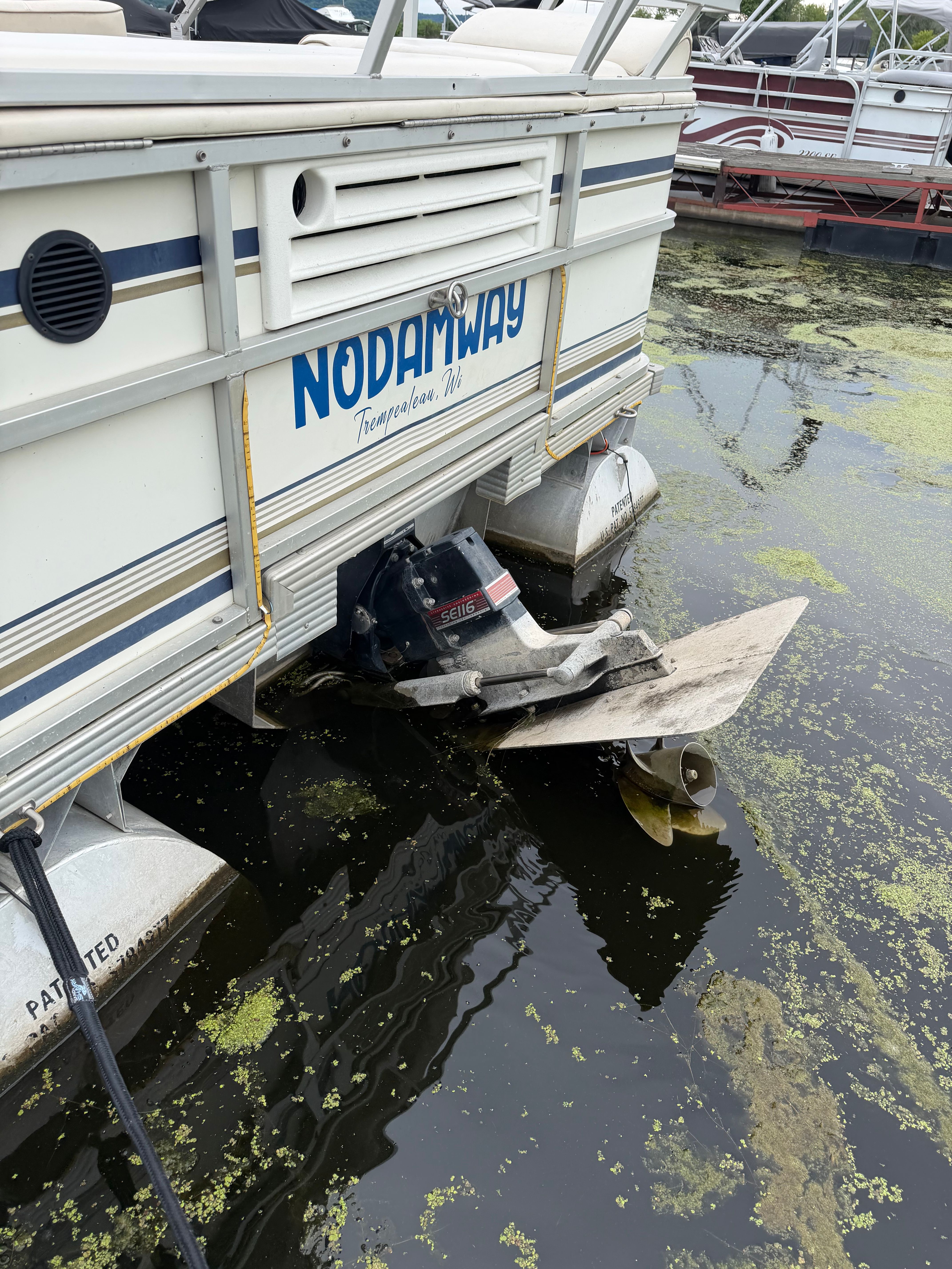 The stern of a 2000 Crest Grand Caribbean in water, surrounded by algae.