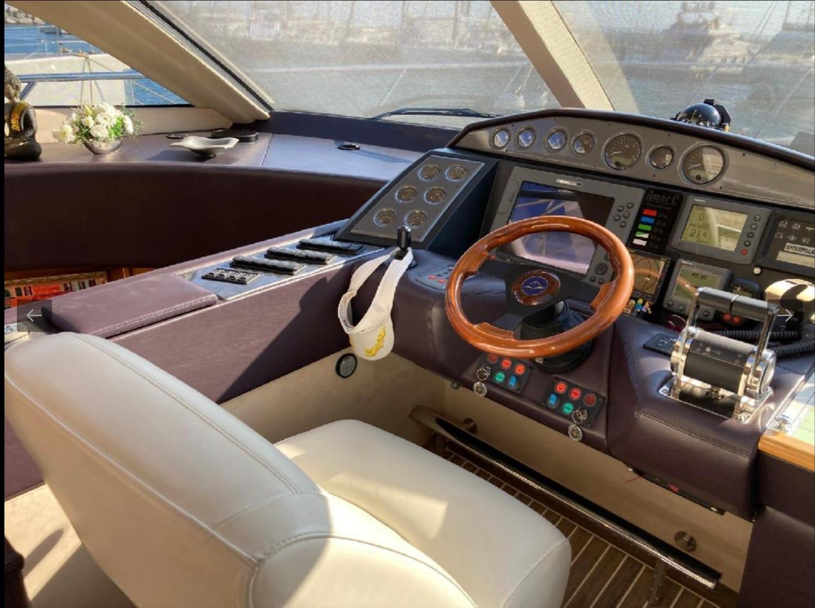 Interior cockpit of a 2005 Sealine T60 yacht with modern controls and wooden steering wheel.