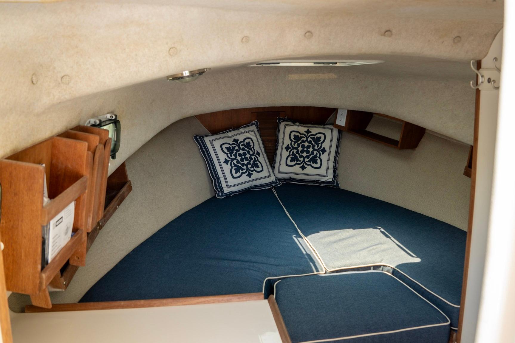Interior cabin of 2006 Atlas Boat Works Acadia 25, featuring cozy bedding and nautical decor.