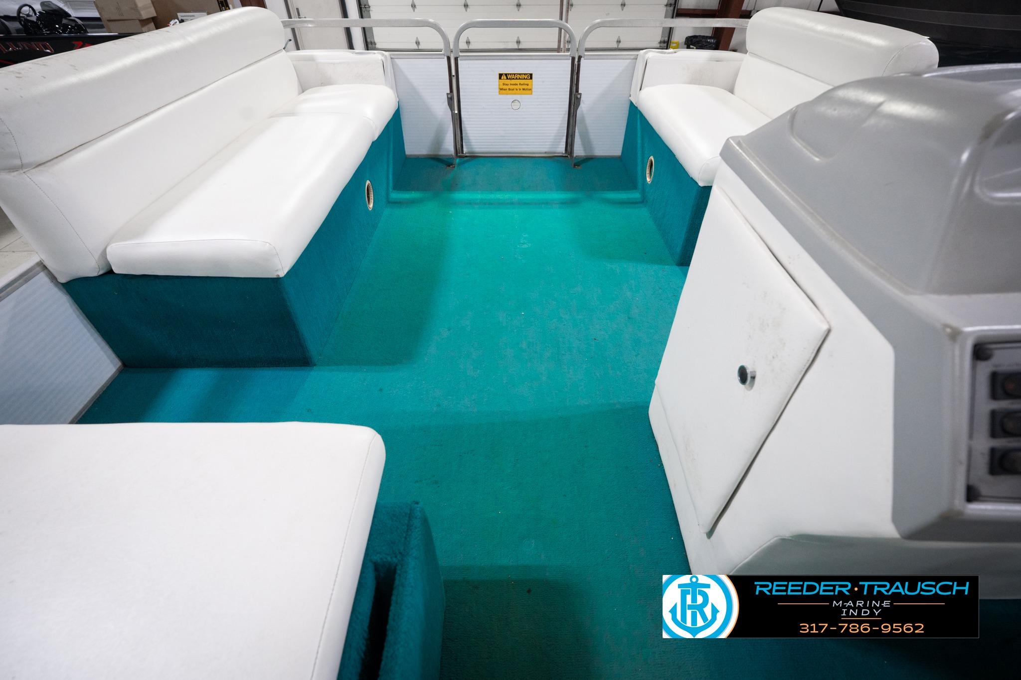 Interior of a 1992 Godfrey Sweetwater boat with white seating and teal flooring.