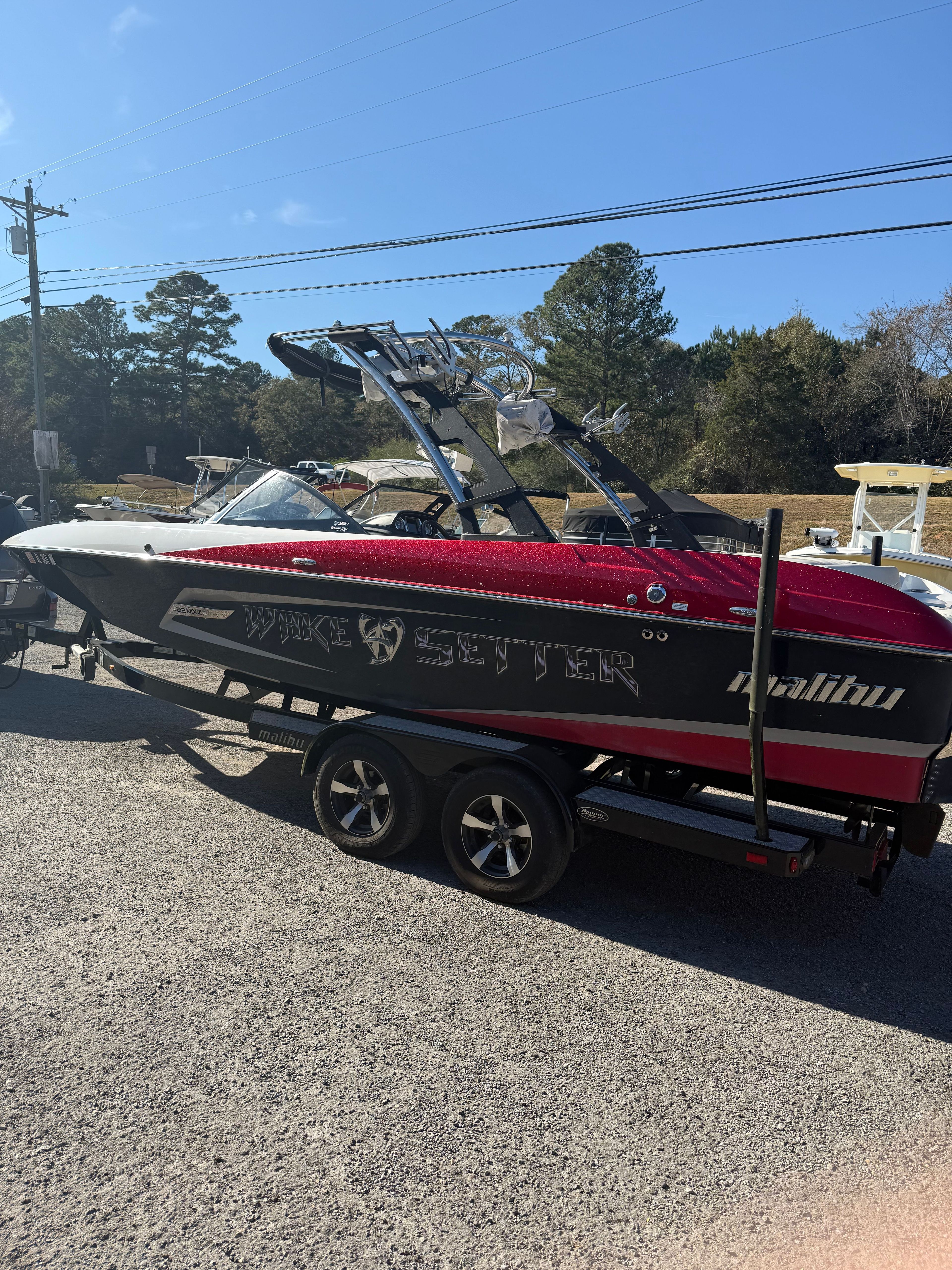 A red Malibu Wakesetter 22 MXZ boat on a trailer, ready for transport.