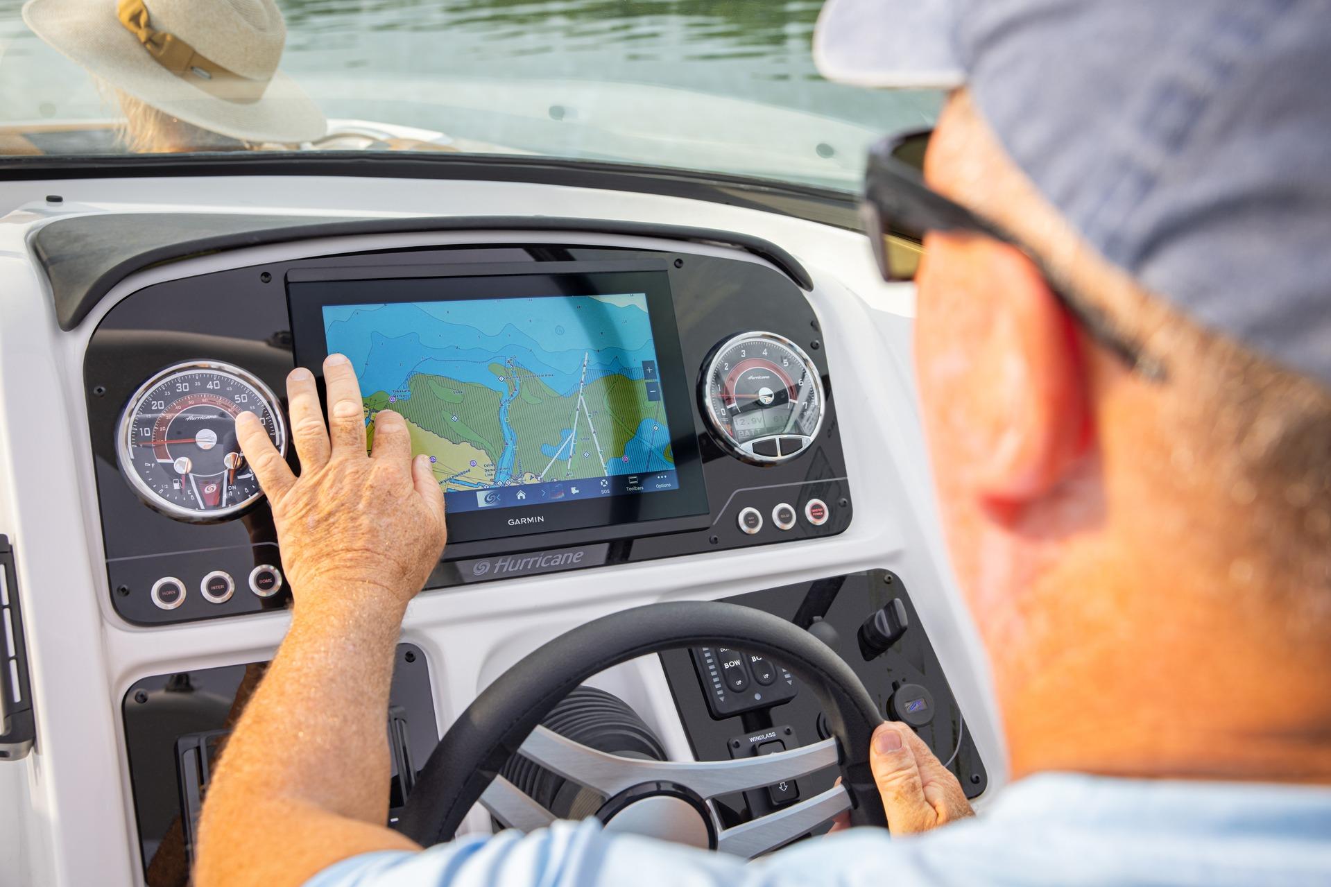 Man navigating 2026 Hurricane SunDeck 2690 OB with touchscreen GPS system.