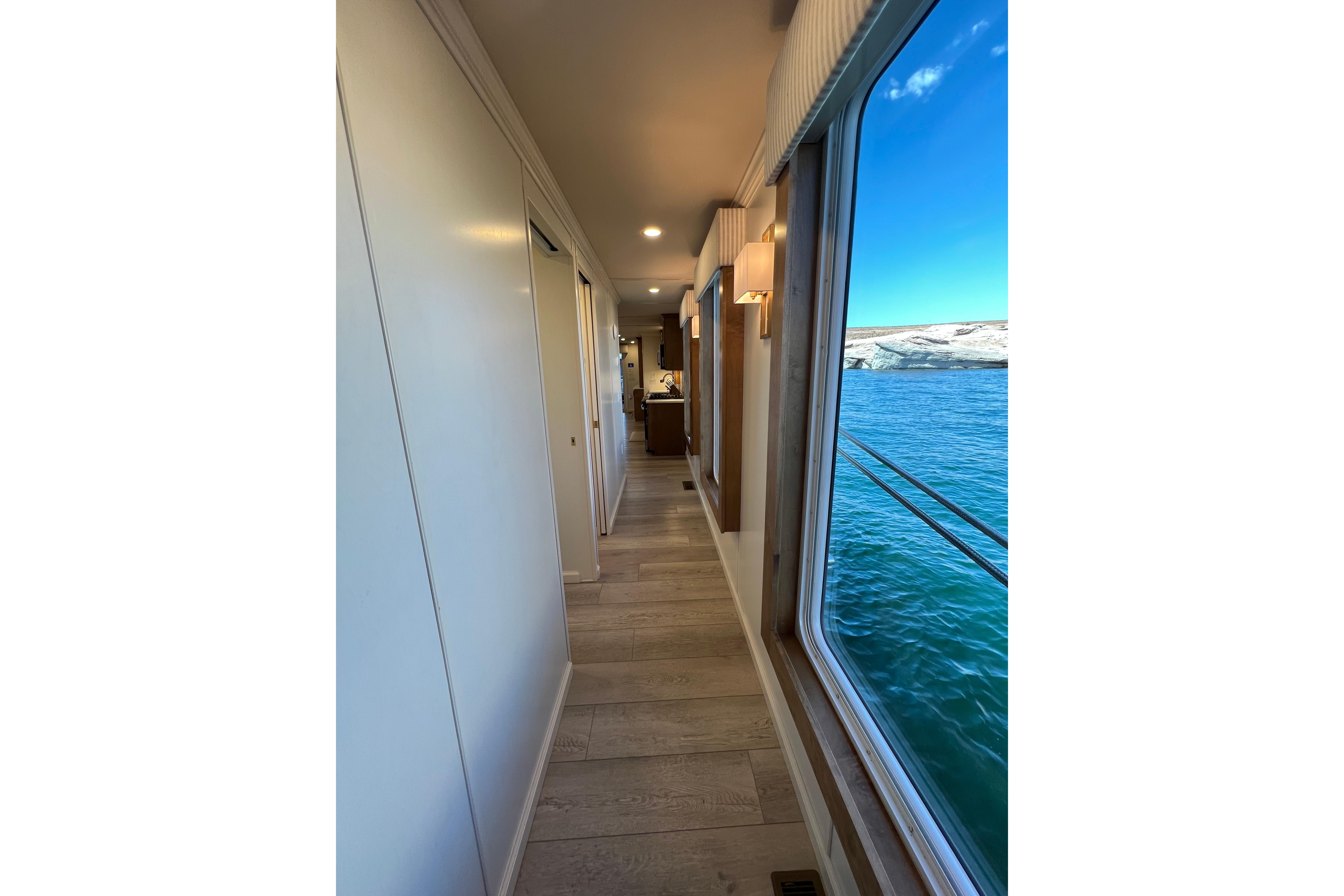 Hallway view inside 2025 Sumerset Excellence Multiple Shares houseboat, featuring large windows and scenic water view.