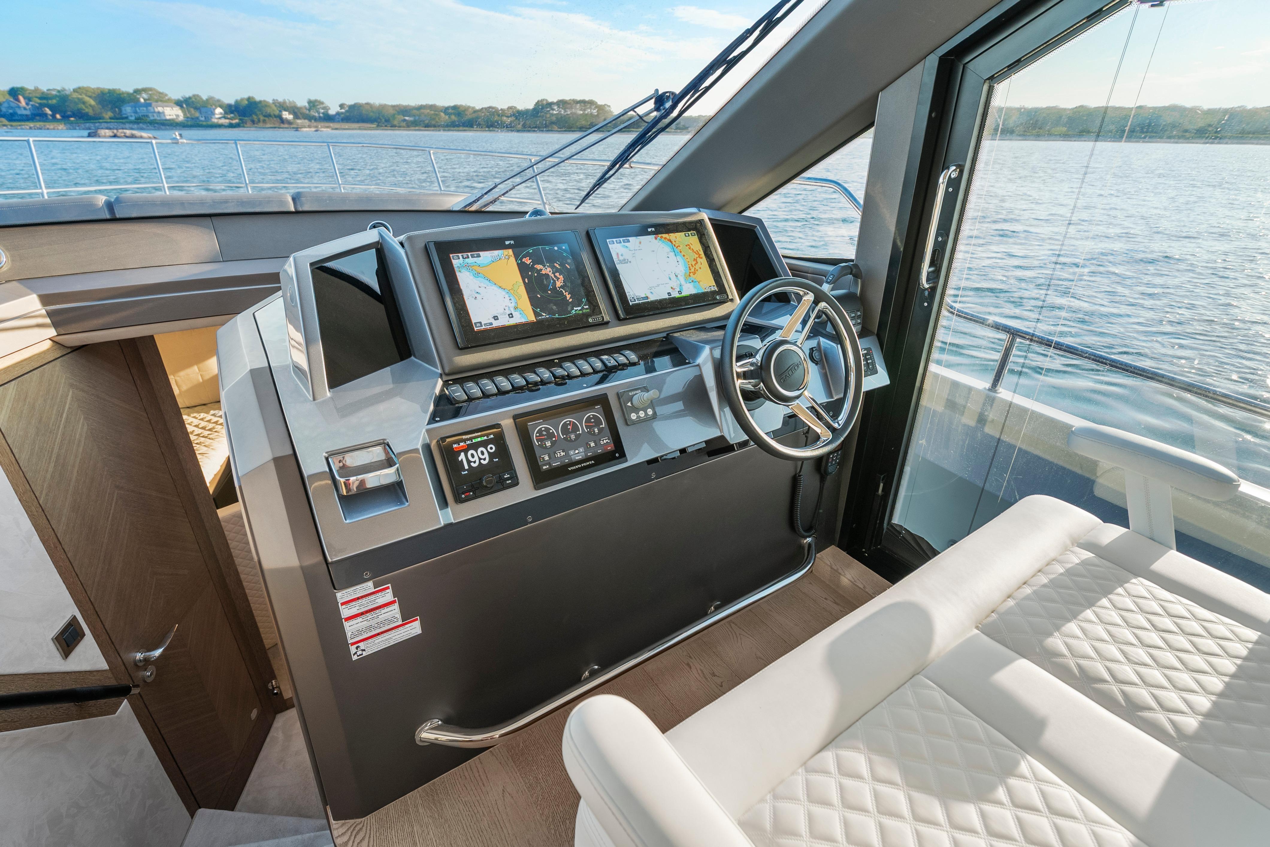 Helm of 2023 Galeon 400 Fly yacht with navigation screens and steering wheel.