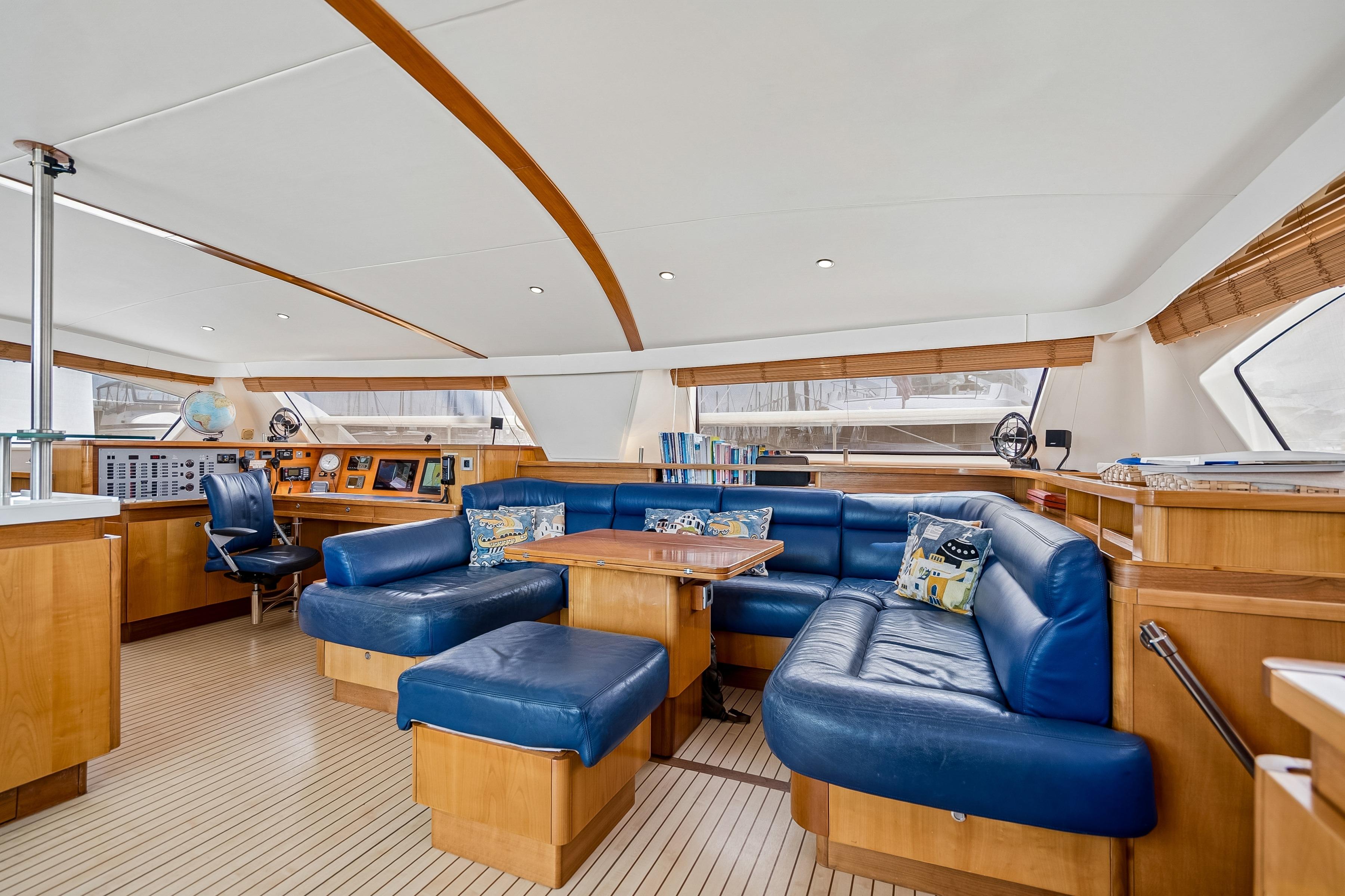 Luxurious interior of 2009 Catana 65 yacht with blue leather seating and wooden accents.