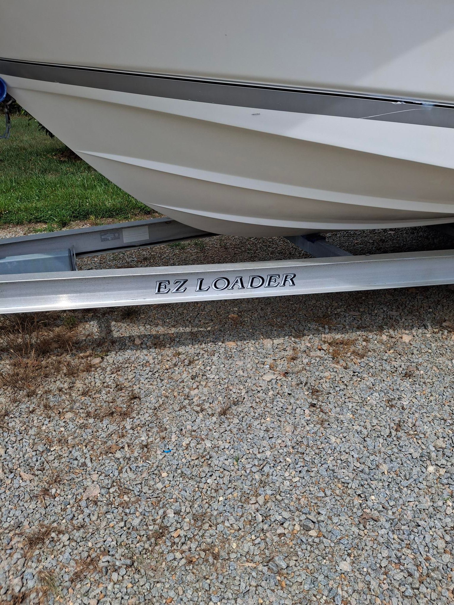 A 2008 Wellcraft 252 Coastal boat on an EZ Loader trailer on gravel.