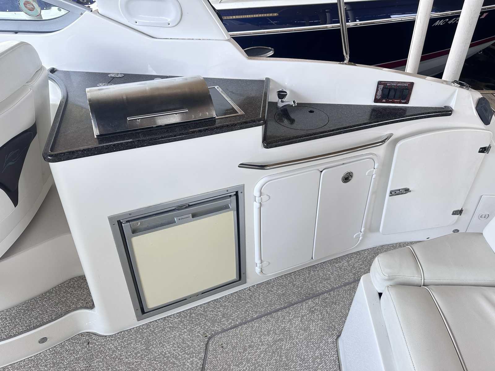 2014 Rinker 310 Express Cruiser interior with kitchenette and seating area.