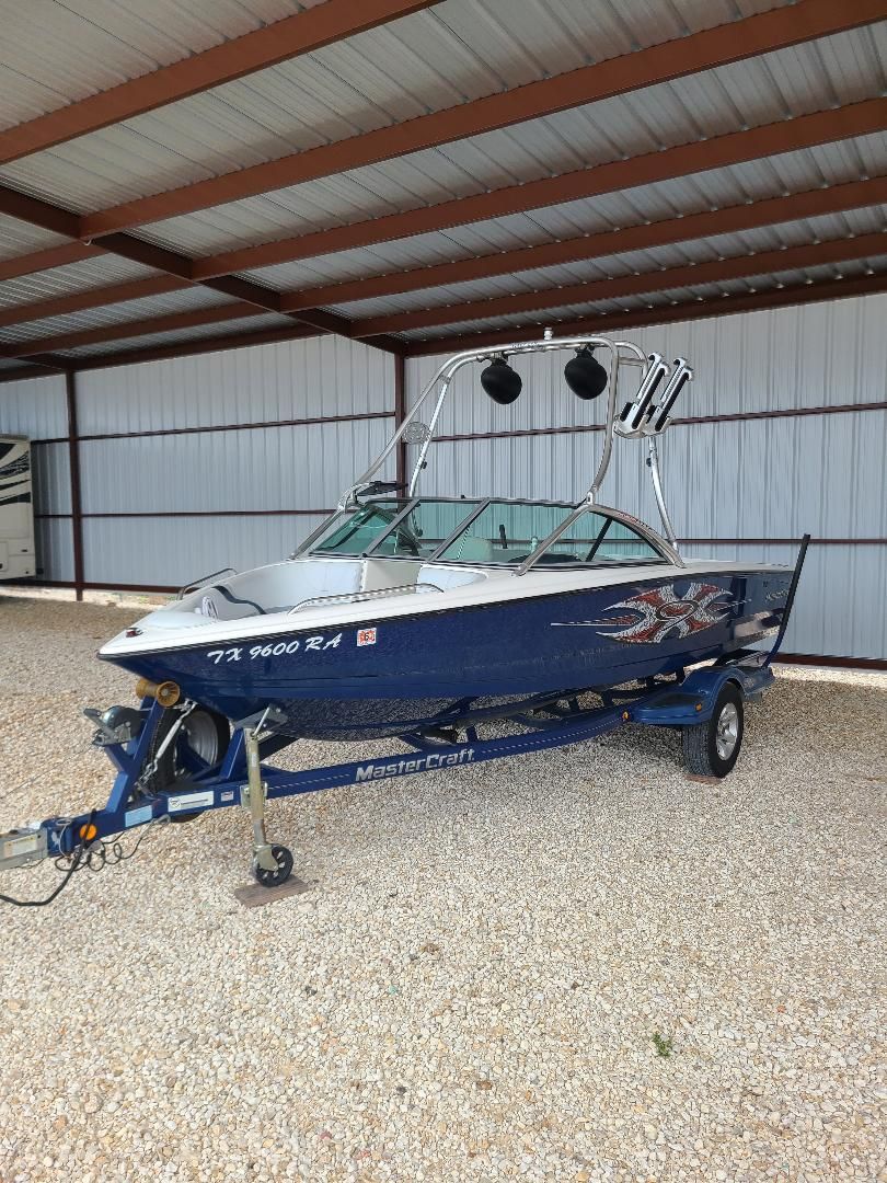 2003 MasterCraft X-9 boat on trailer in covered storage area.