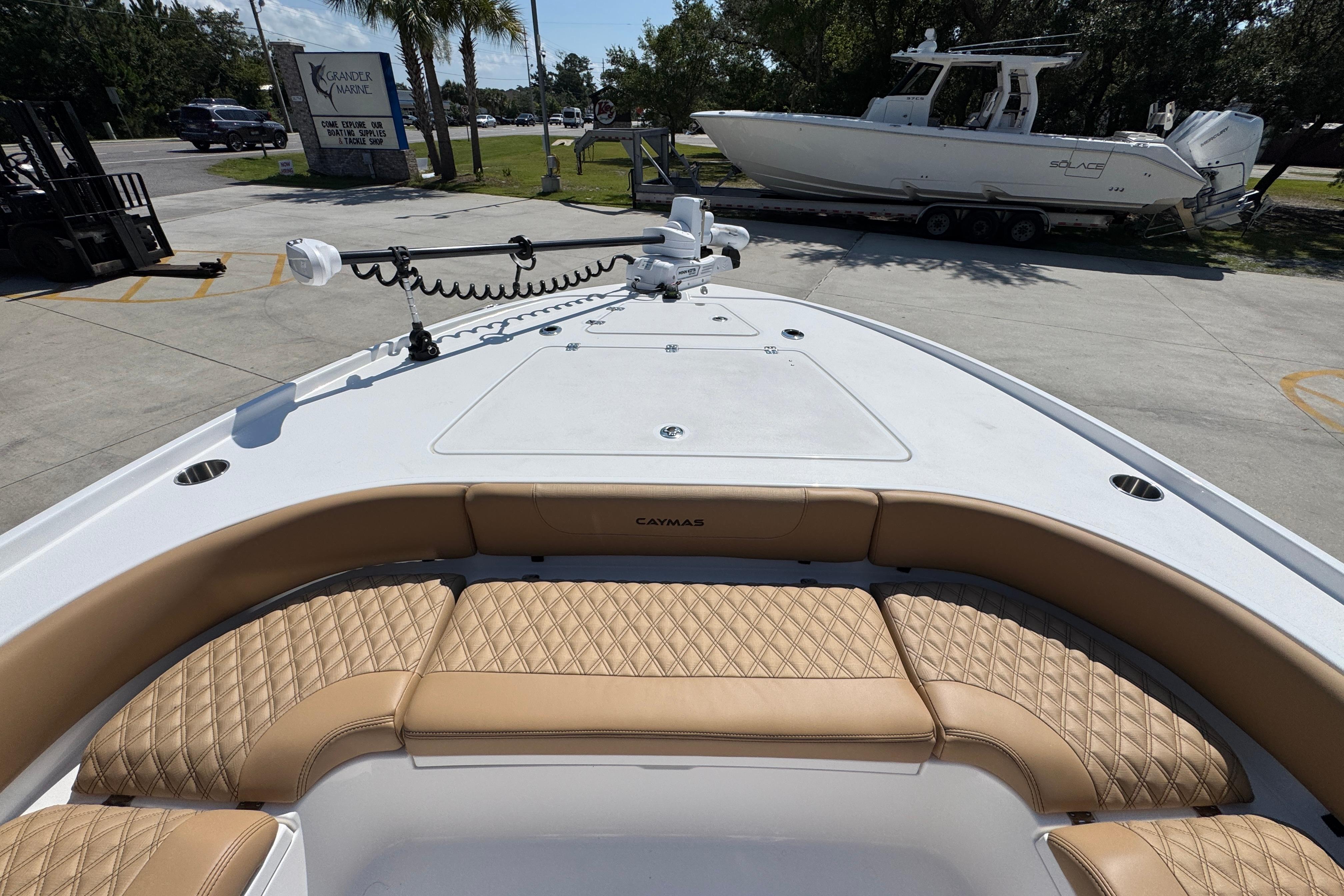 2027 Caymas 26 HB boat with tan seating and trolling motor, parked outdoors.