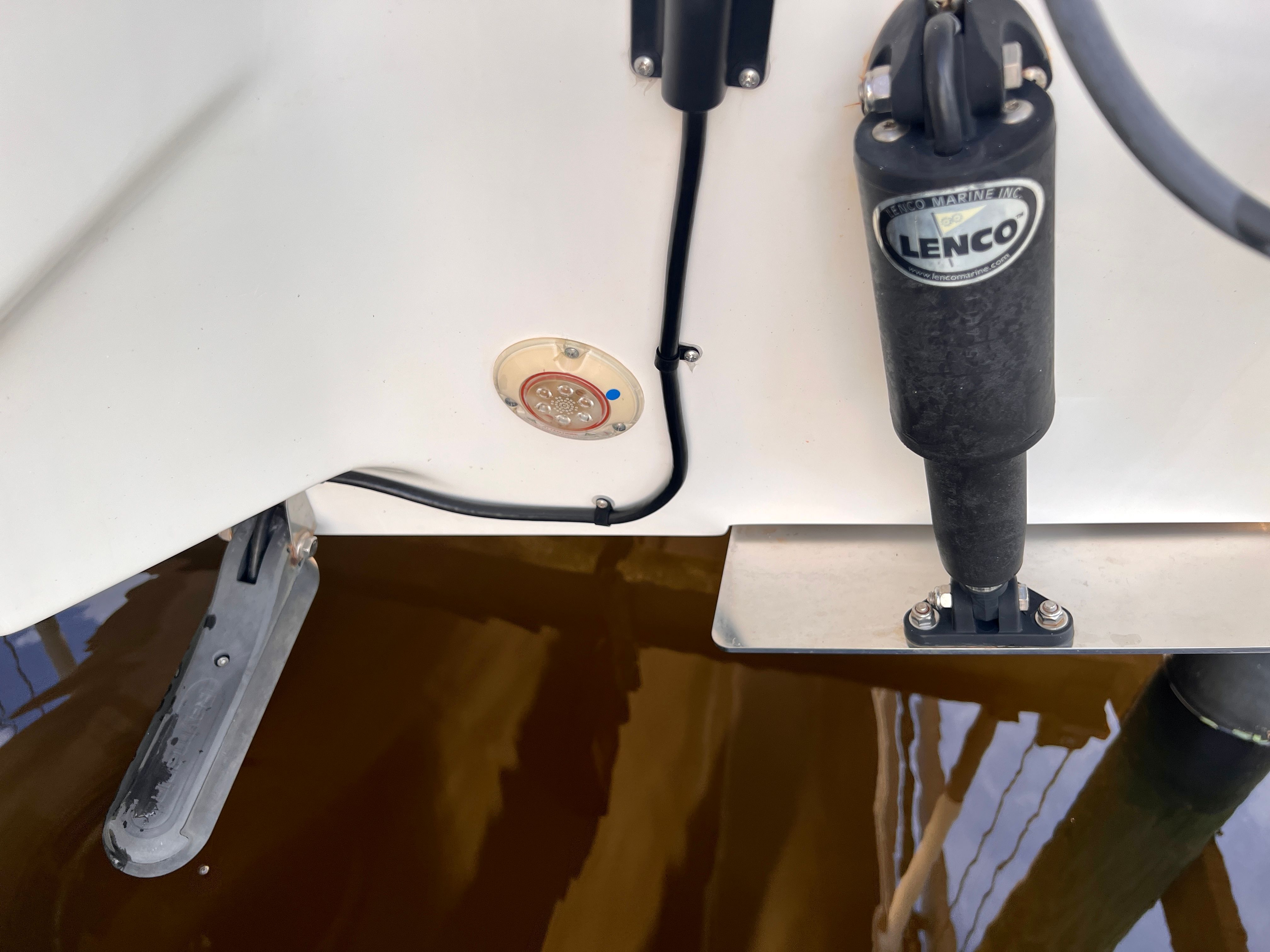 Close-up of a boat part with Lenco trim tab in the water.