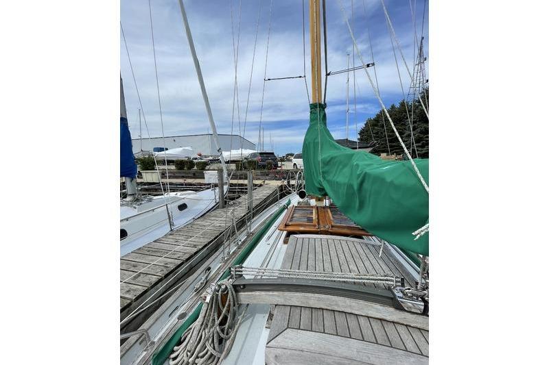 1980 Ta Shing Baba 30 sailboat docked, featuring wooden deck and green sail cover.