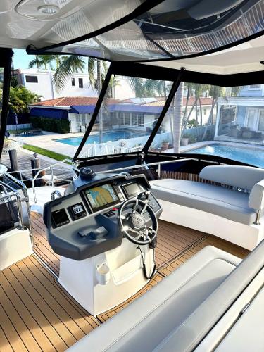 Luxury 2022 Aquila 44 yacht interior with modern helm and seating, overlooking waterfront homes.