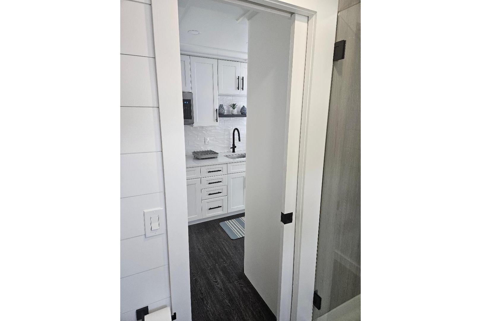 Modern kitchen interior of 2021 East Coast Houseboats Freedom 40, featuring sleek white cabinetry.