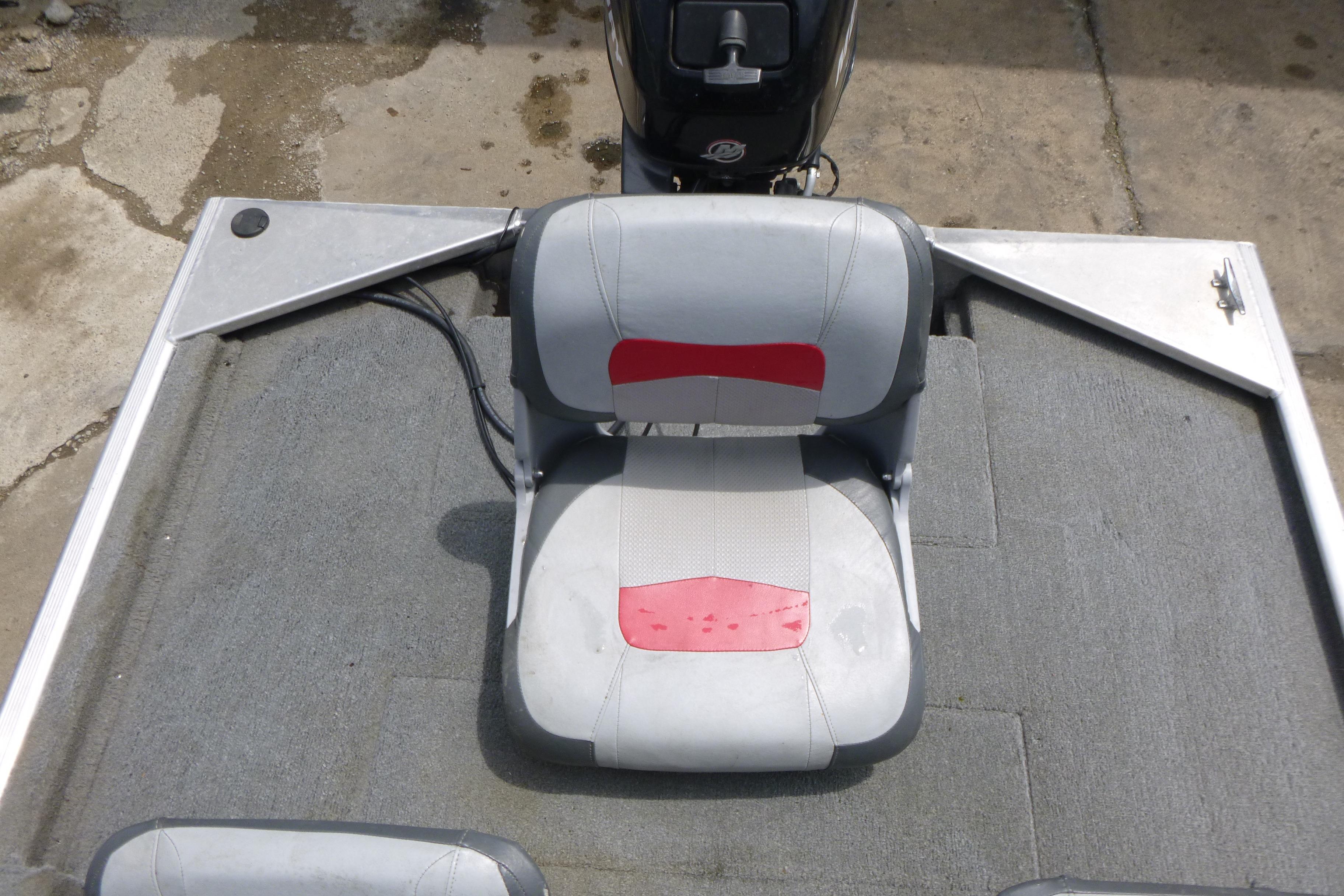 2011 Tracker Pro Angler 16 boat seat with gray and red upholstery on a carpeted deck.