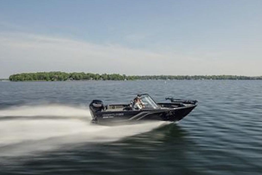 2026 Crestliner 1650 Hawk WT speeding on a serene lake under a clear sky.