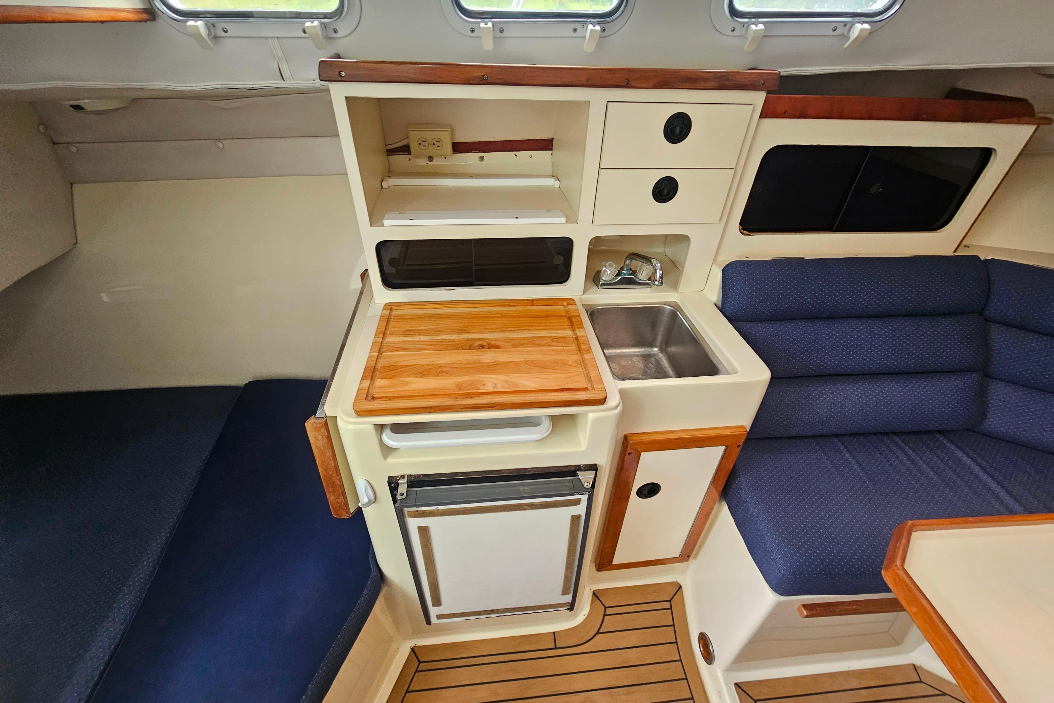 Interior of 1999 Albin 28 Tournament Express with compact kitchen and seating area.