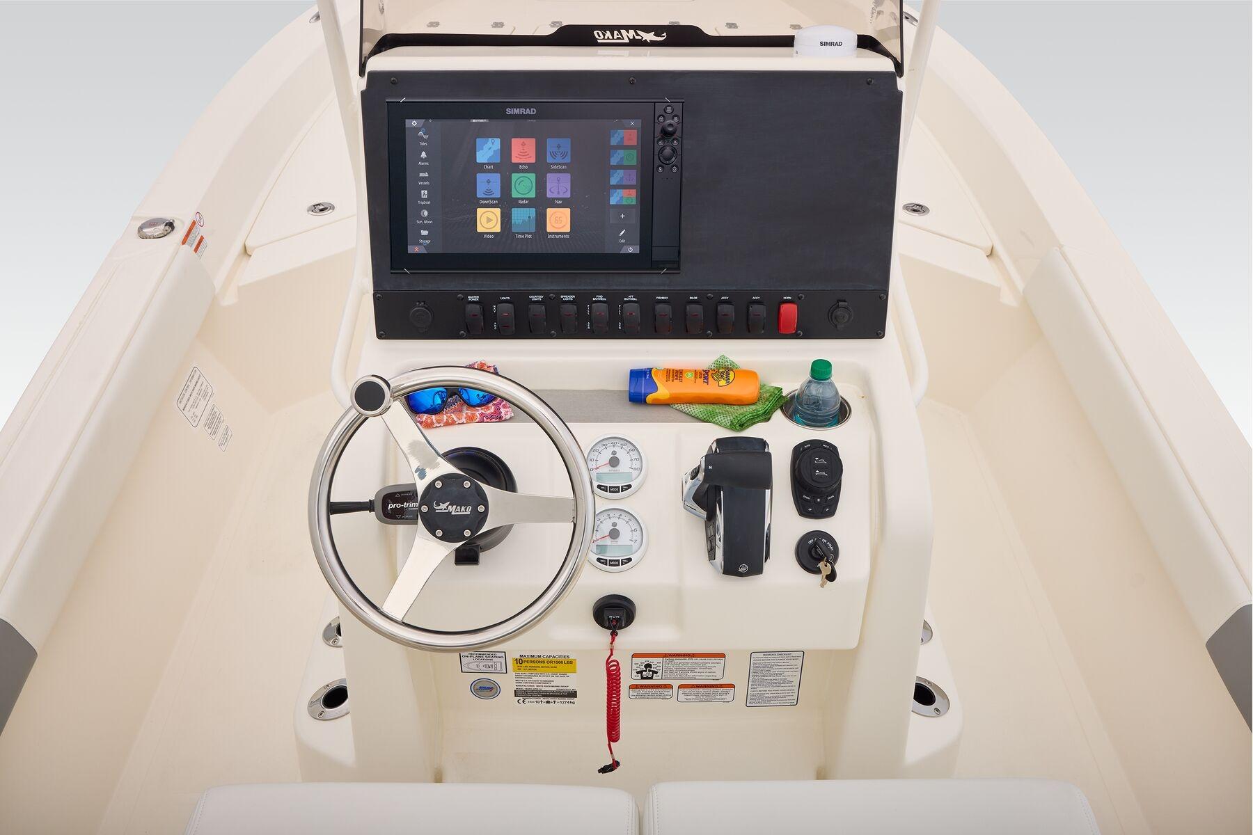 2026 Mako 24 APEX boat dashboard with steering wheel, controls, and touchscreen display.