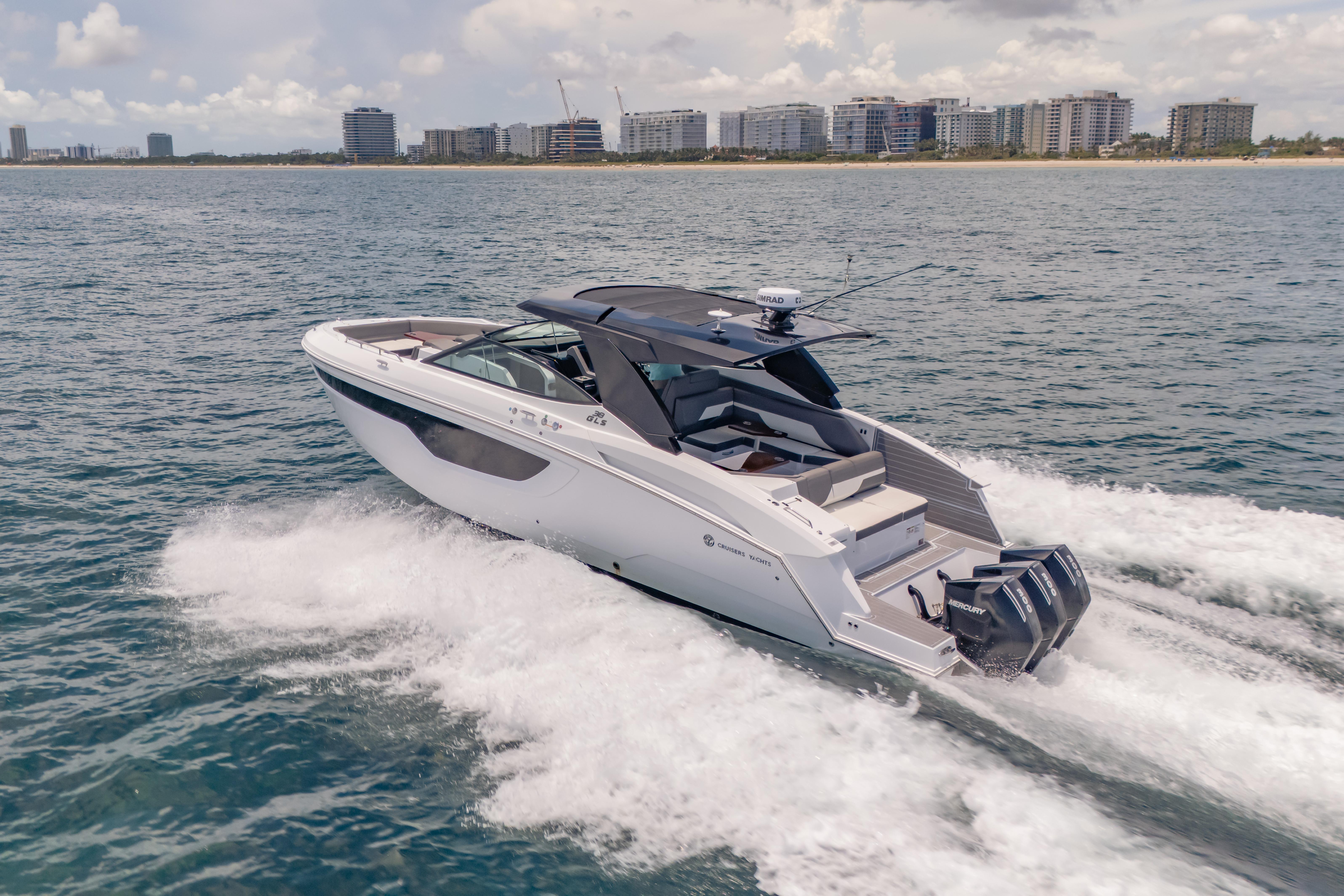 2021 Cruisers Yachts 38 GLS speeding on ocean near city skyline.