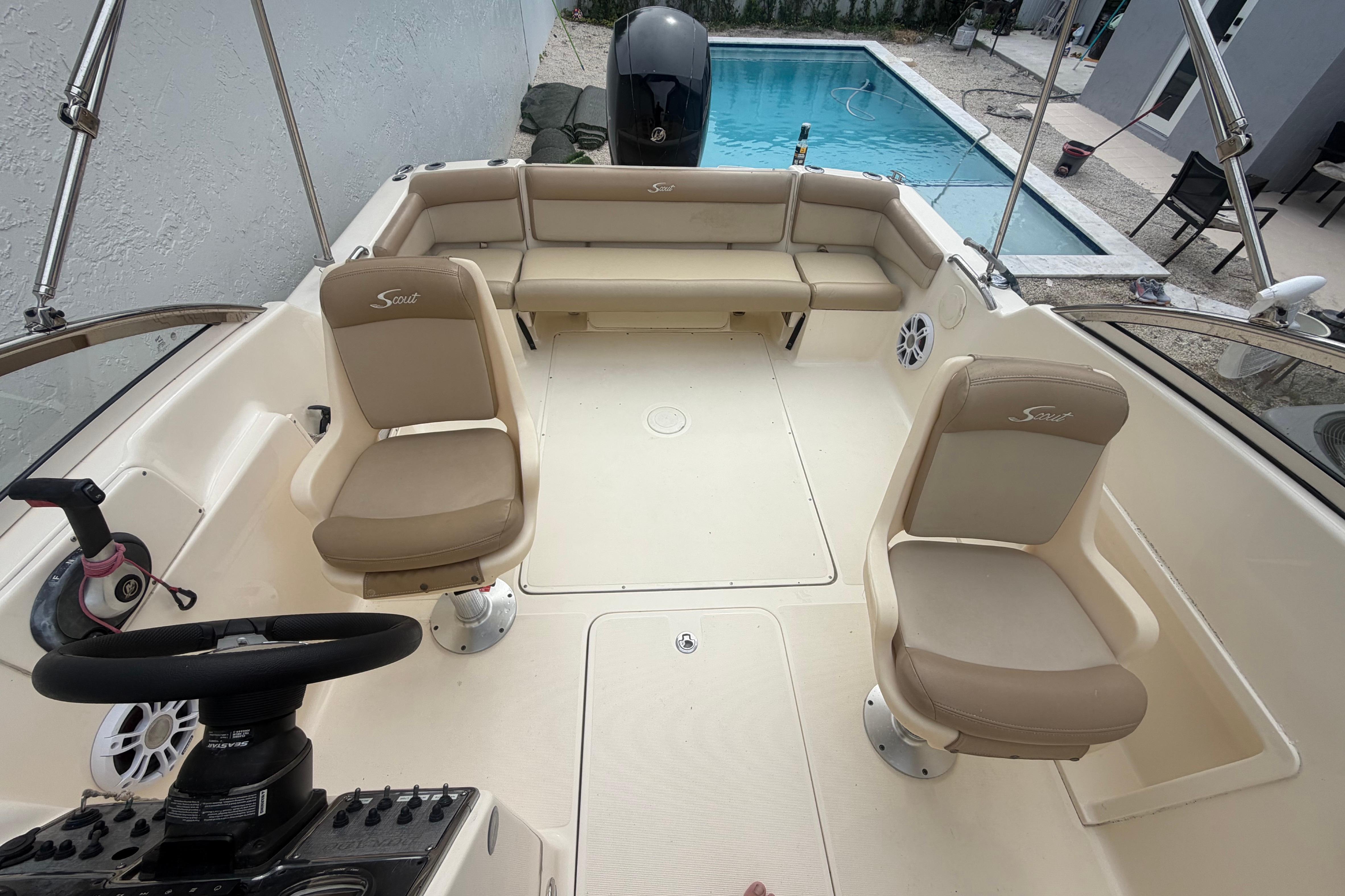 2023 Scout 210 Dorado boat interior with beige seating, near a swimming pool.