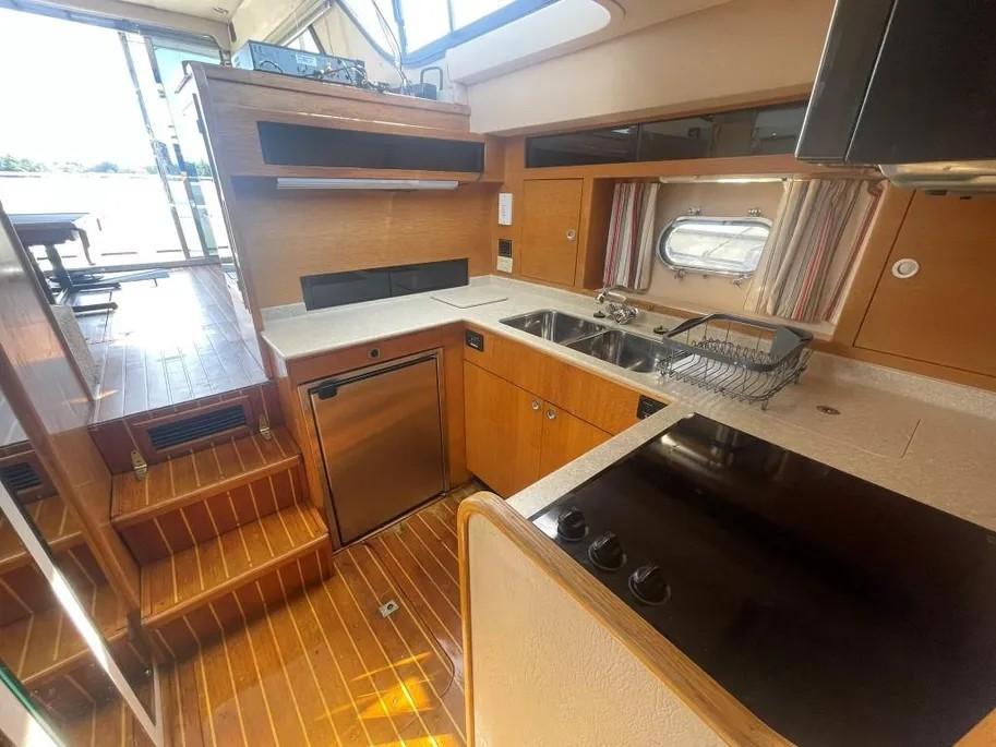 1985 Princess Sedan Flybridge yacht kitchen with wooden flooring, modern appliances, and ample counter space.