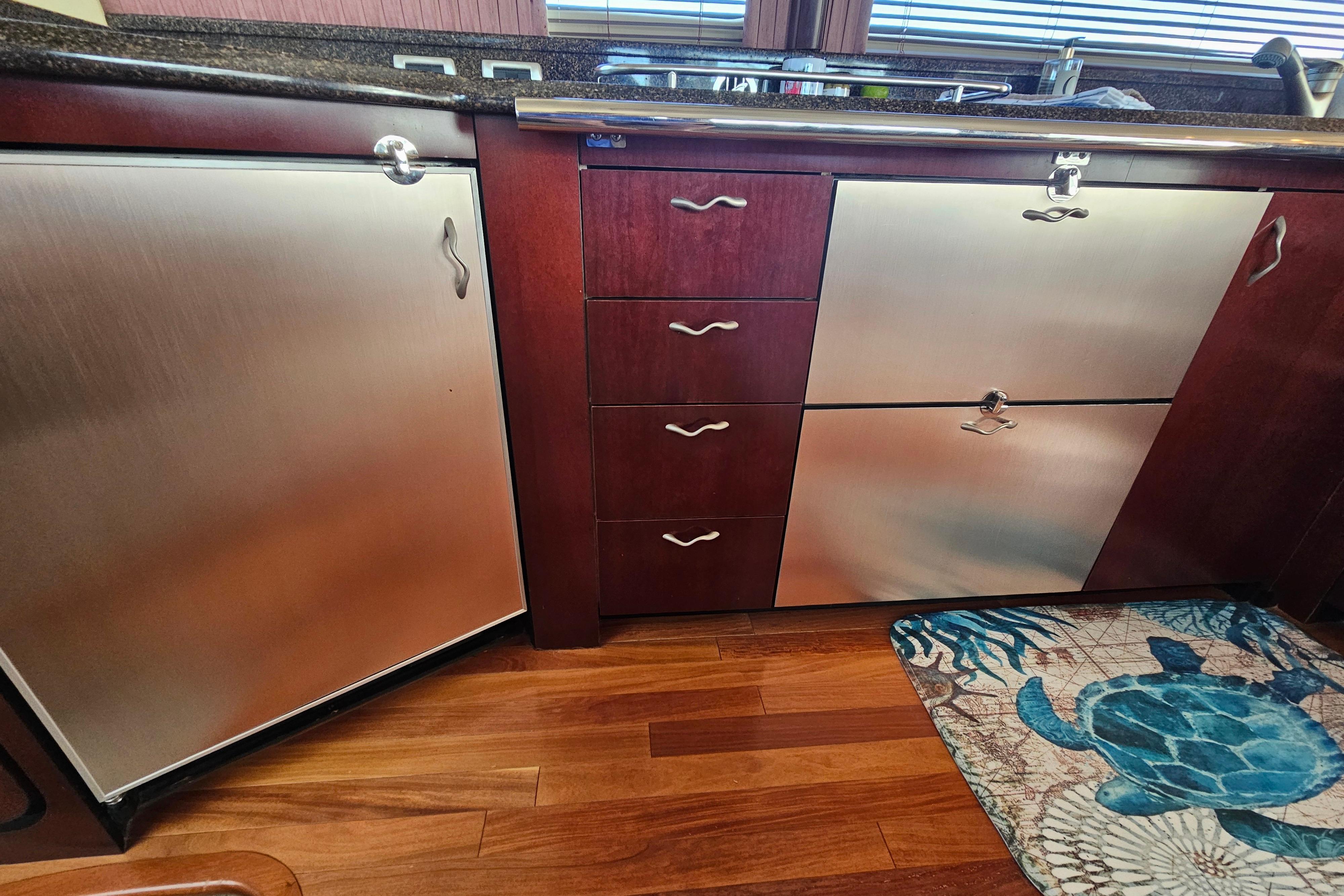 Luxury yacht kitchen with stainless steel appliances, wooden cabinets, and turtle-themed rug. Sea Ray 580 Sedan Bridge 2006.