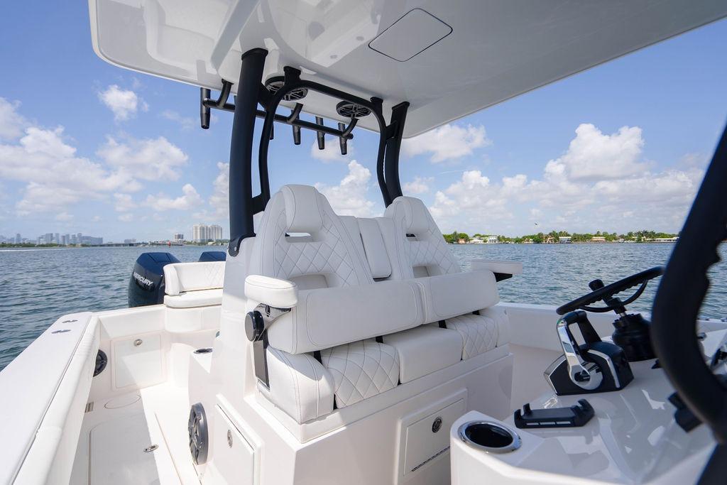 2027 Reef Runner 340 boat interior with white seating, steering wheel, and ocean view.