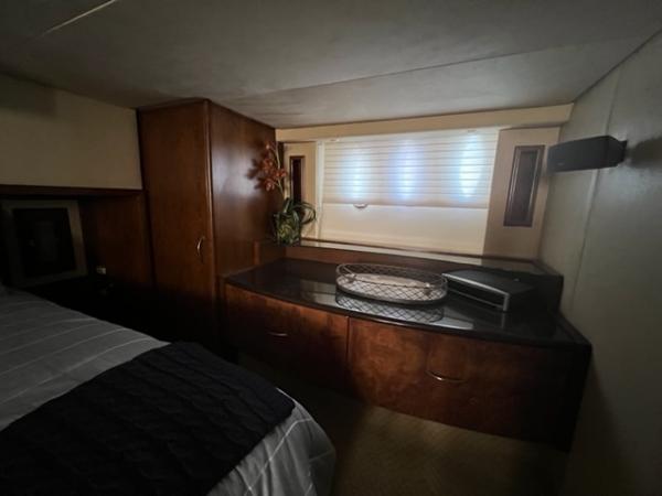 Cozy bedroom interior of 2009 Ovation 52 yacht with wooden cabinets and window.