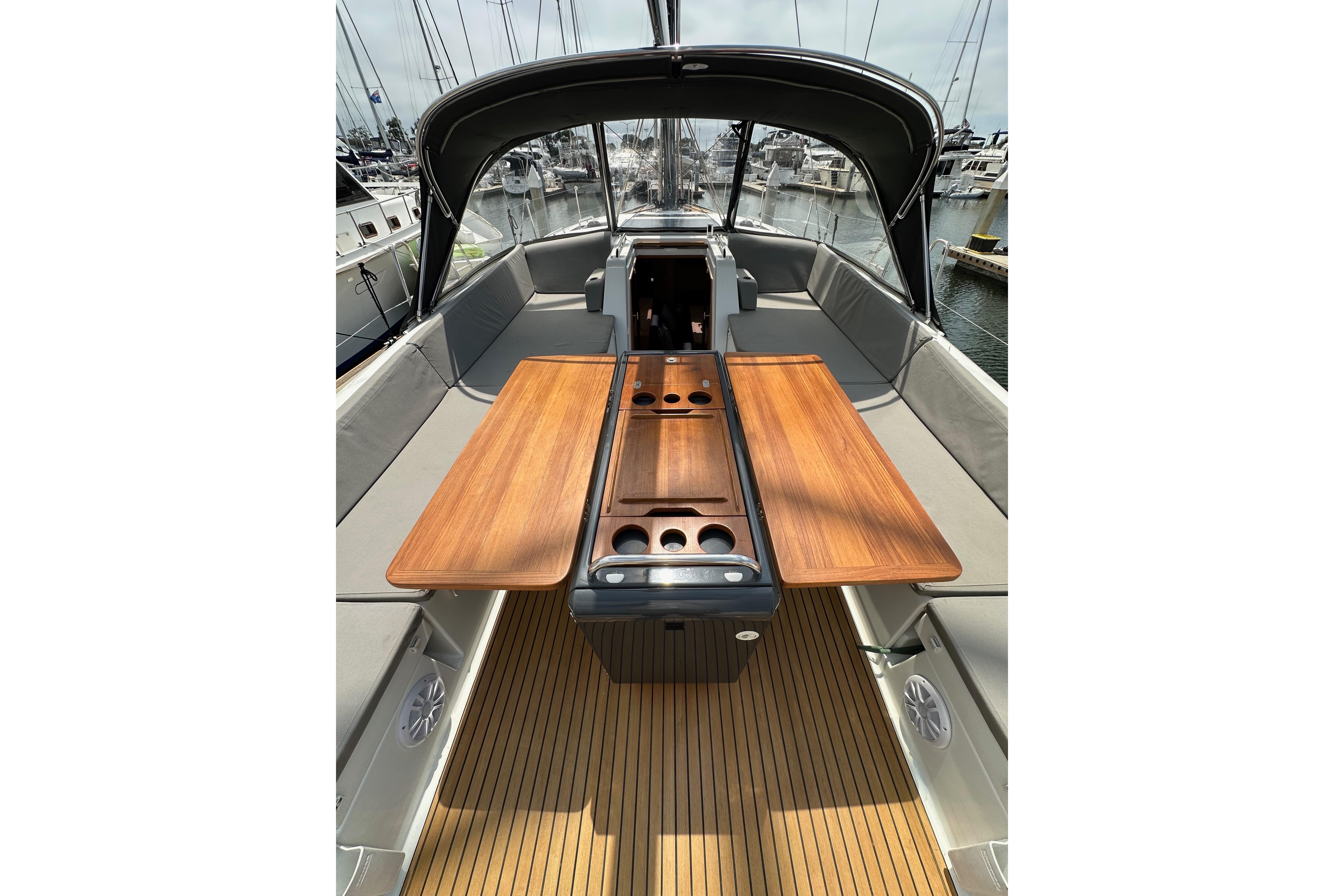 2018 Jeanneau 54 yacht cockpit with wooden table and seating, docked at marina.