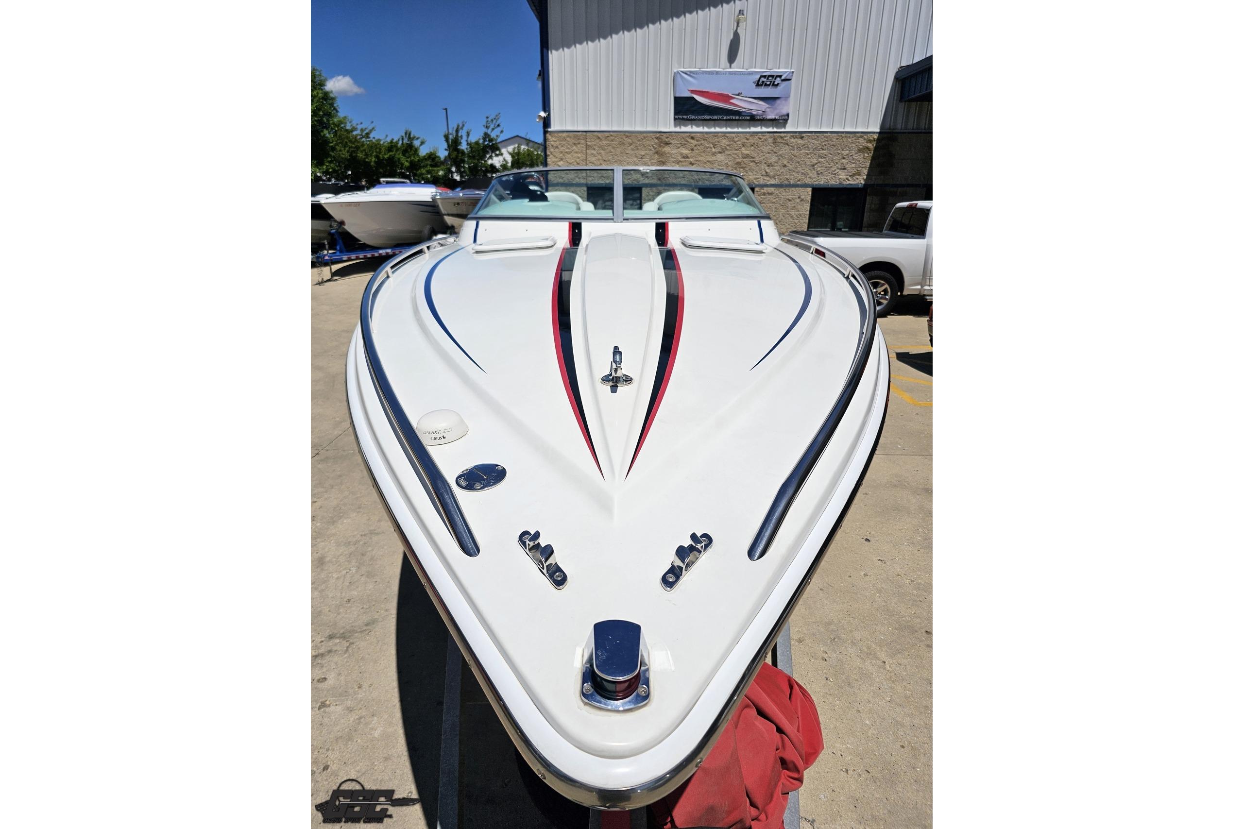 2005 Formula 271 FASTech boat with sleek white and red design, parked outdoors.