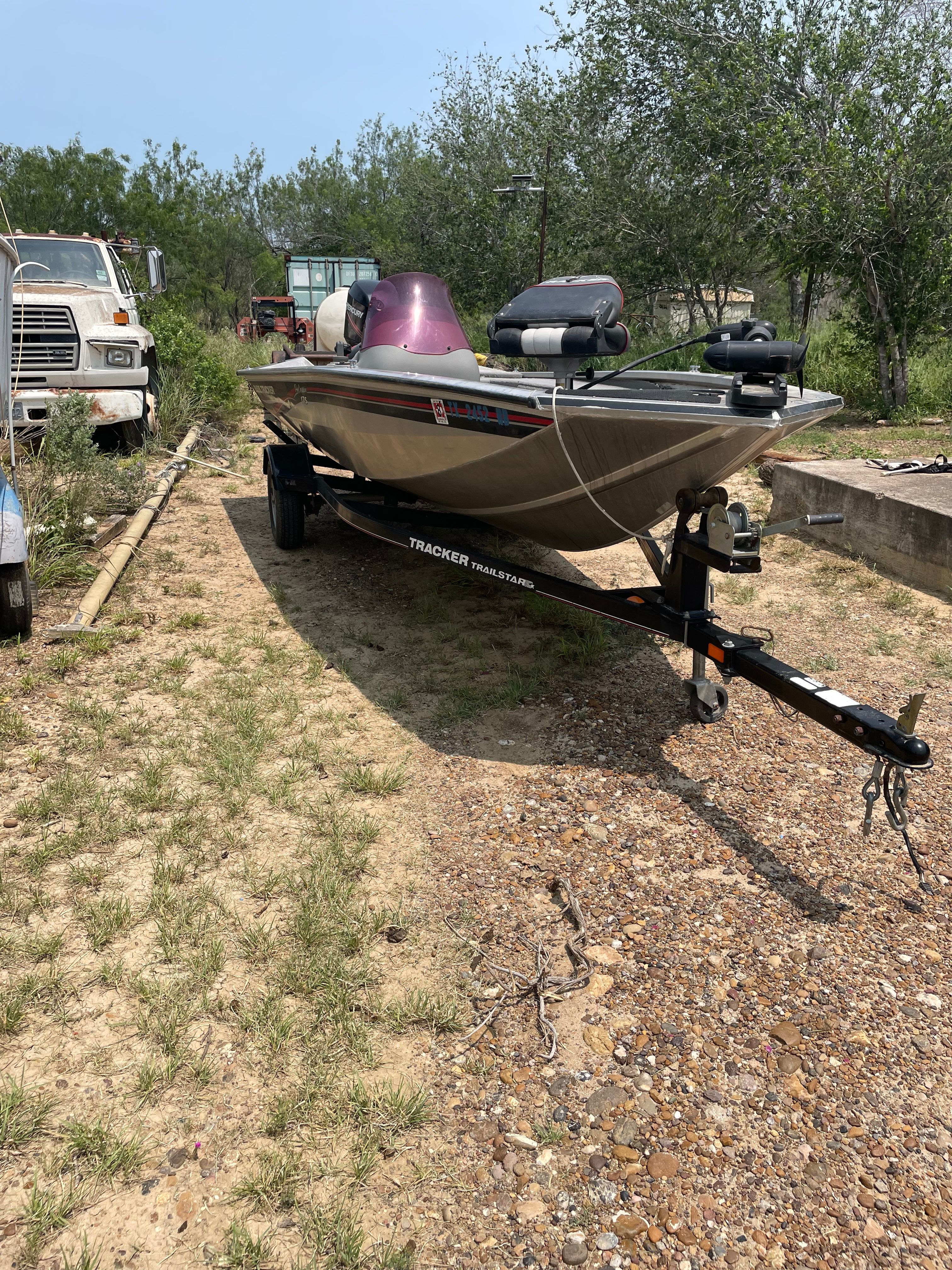 A 2009 Tracker Pro Crappie 175 on a trailer, surrounded by trees and vehicles.