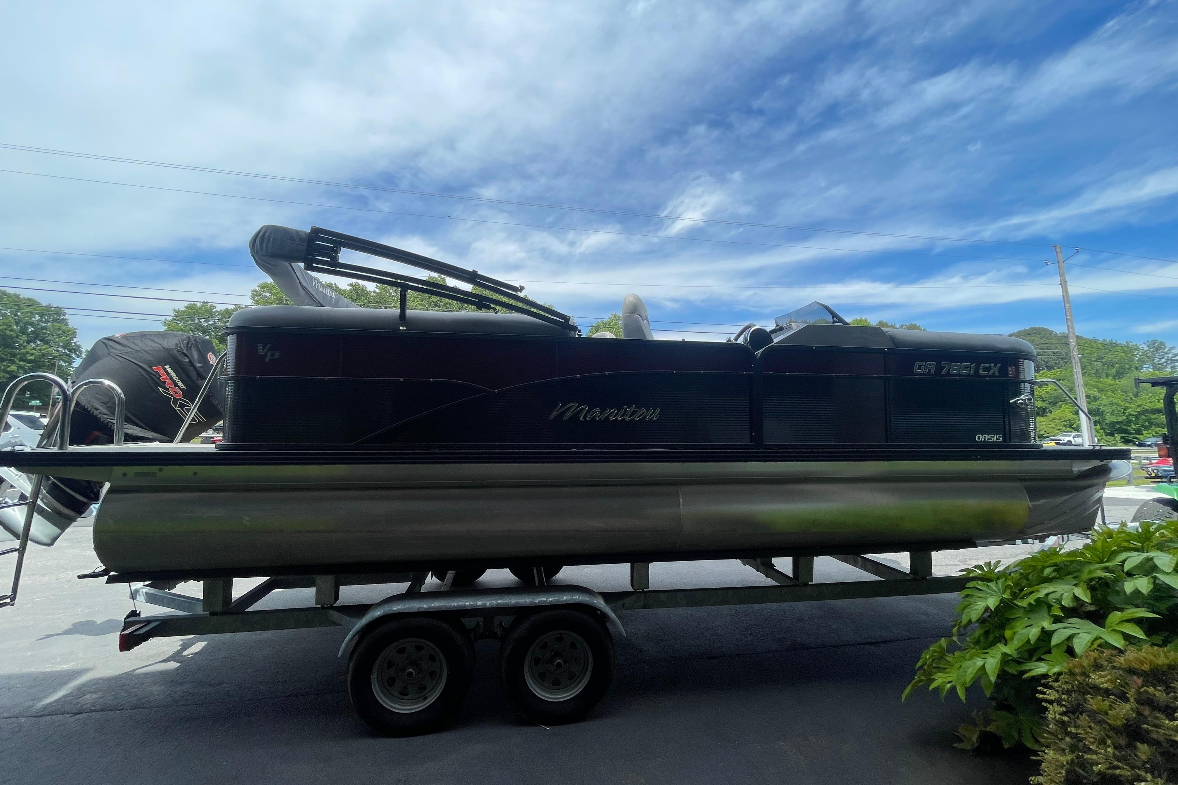 2022 Manitou 23 Oasis pontoon boat on trailer under a clear blue sky.