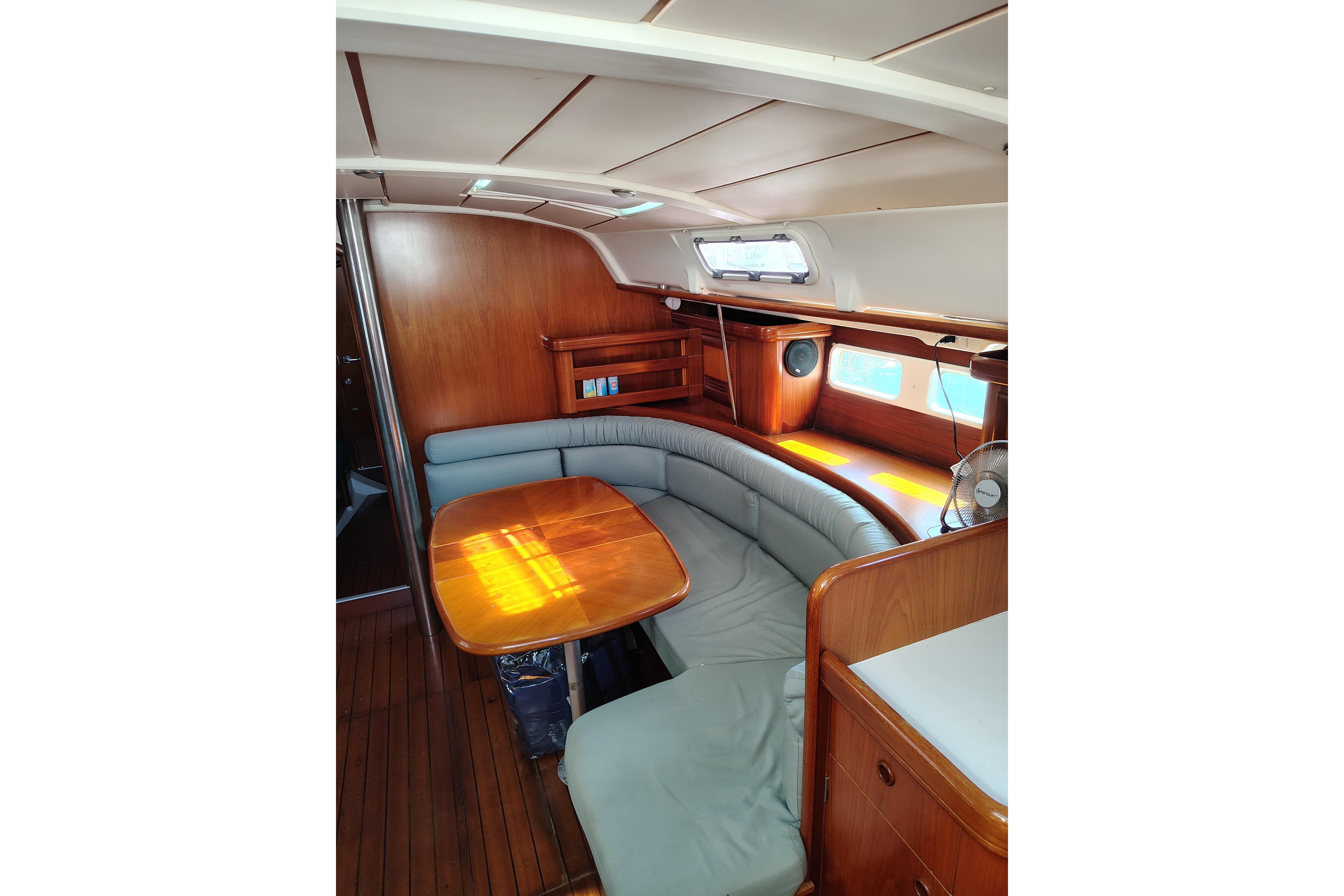 Interior of 2001 Beneteau Oceanis 411 sailboat with wooden furnishings and curved seating.