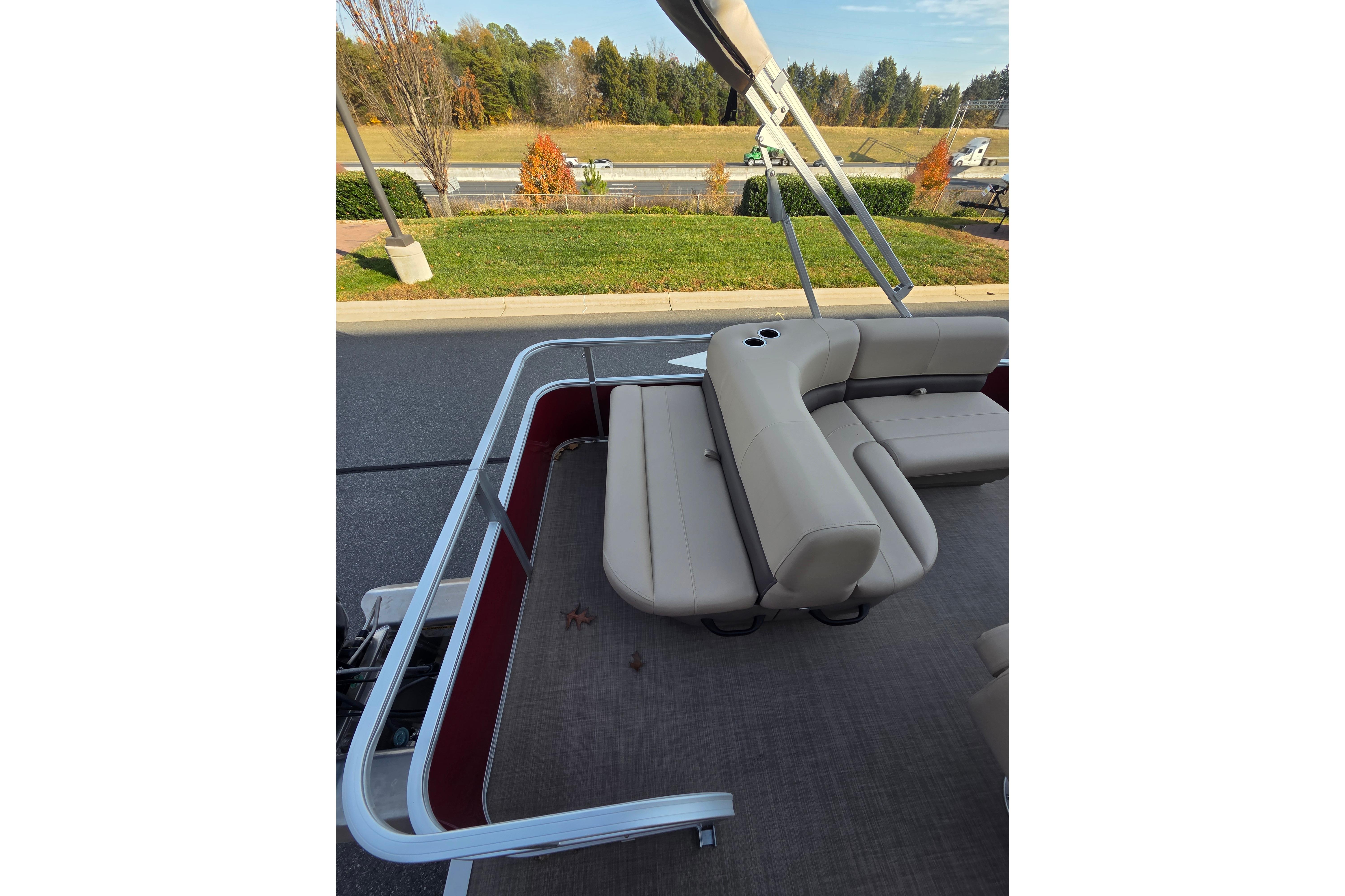 2025 Sun Tracker Party Barge 18 DLX interior with beige seating and cup holders.