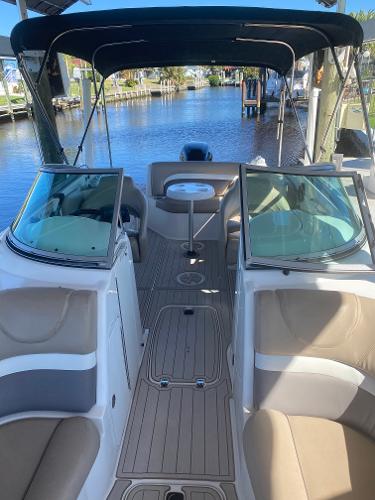 2015 Hurricane SunDeck 2400 OB boat interior with seating and canopy on a calm waterway.
