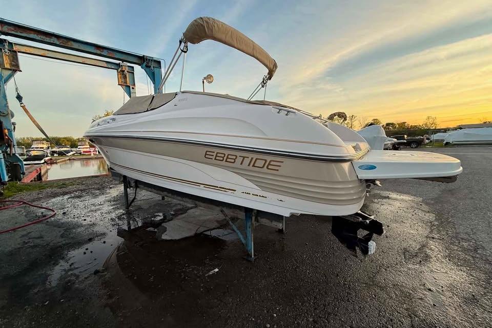 1999 Ebbtide 2300 Bow Rider boat on a stand at sunset.