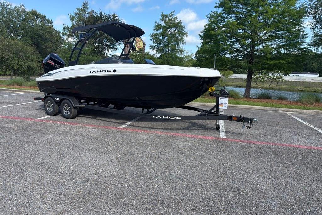 2026 Tahoe T21 boat on trailer in parking lot, surrounded by trees and water.