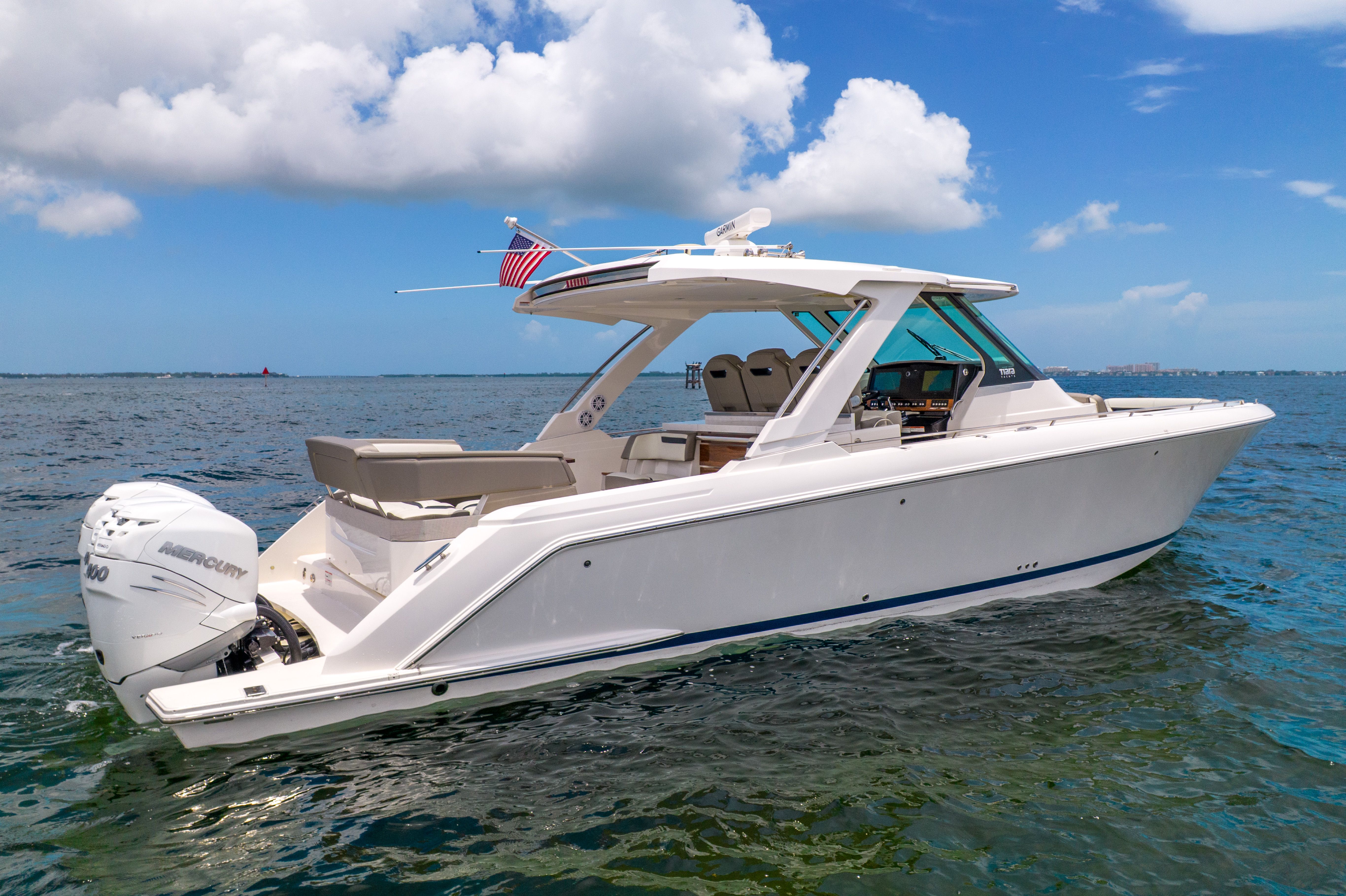 A luxurious 2023 Tiara Yachts 38 LS on calm water under a blue sky.