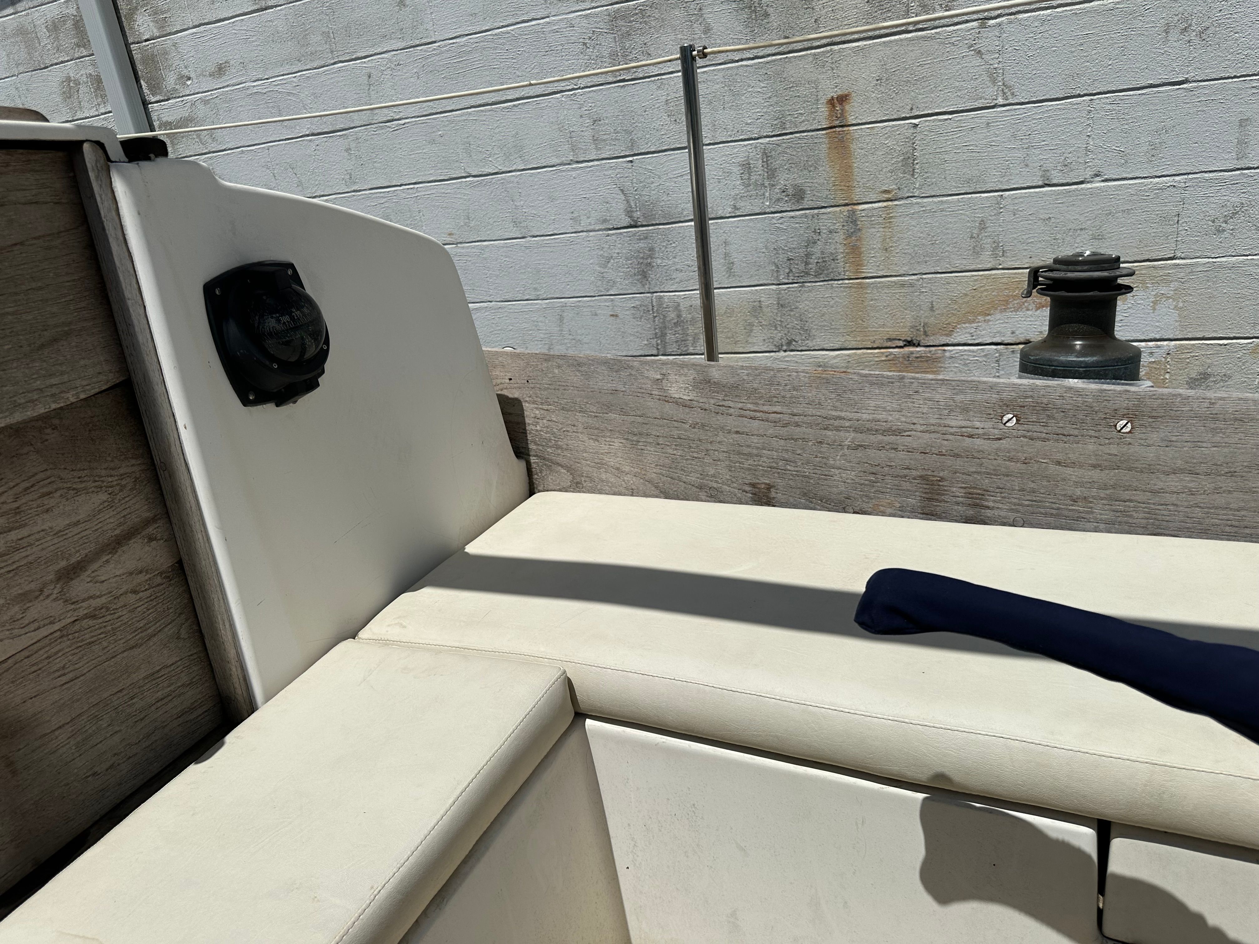 Seating area on a boat with white cushions and wooden walls.