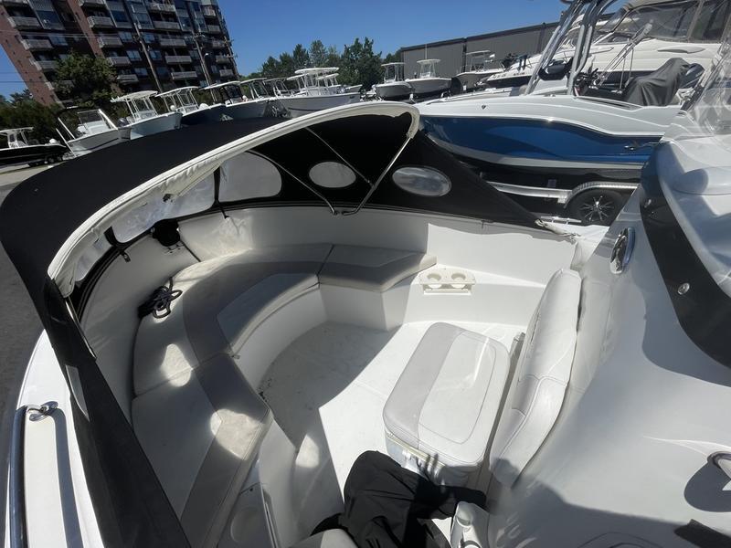 2006 Boston Whaler 210 Outrage boat interior with seating and canopy, docked near other boats.