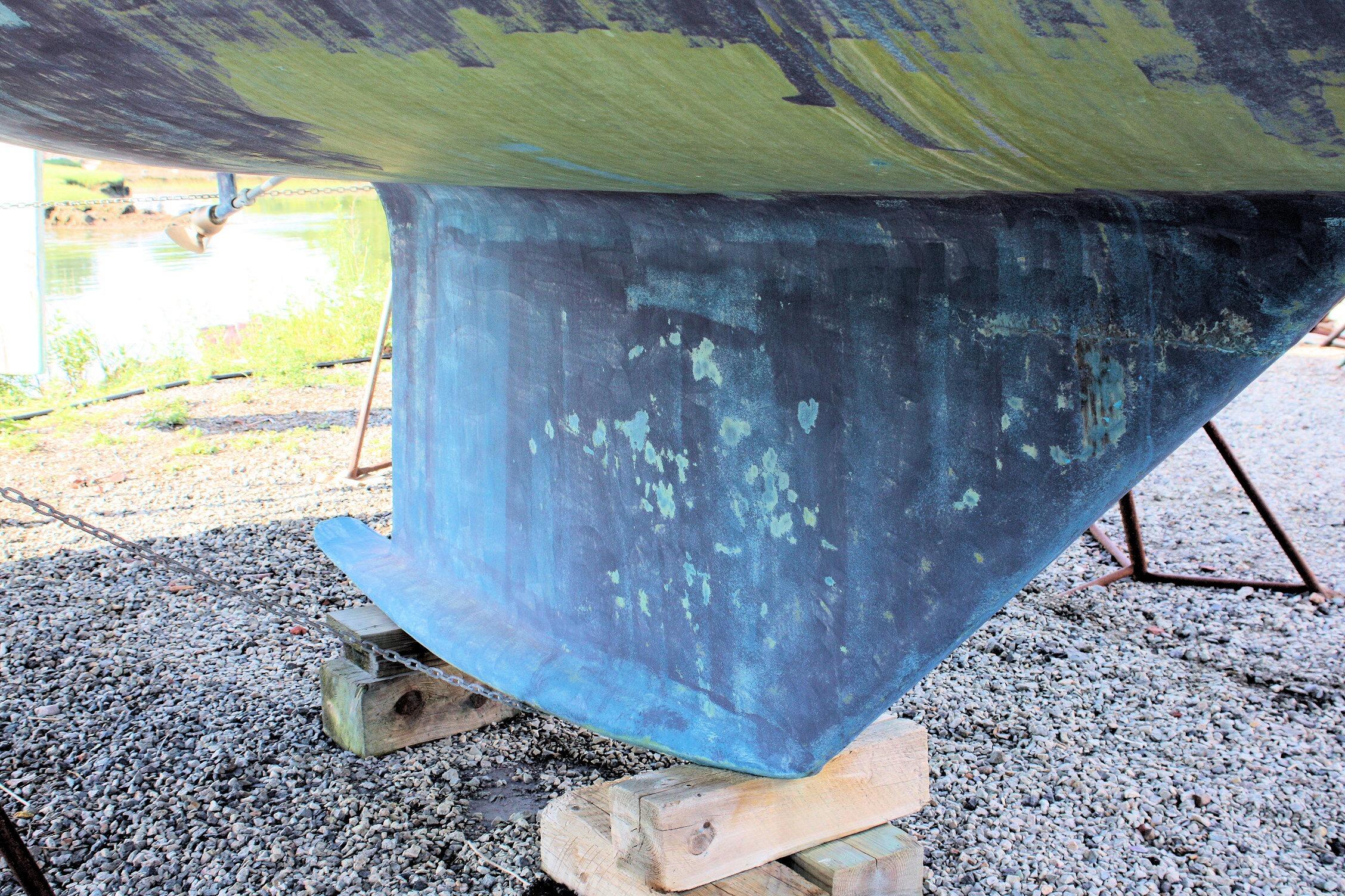 1987 Ericson 38-200 sailboat keel on dry dock, showing weathered blue hull.